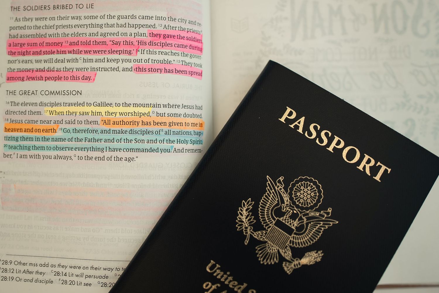 Several United States passports arranged on a surface with bible scripture text visible in the background.