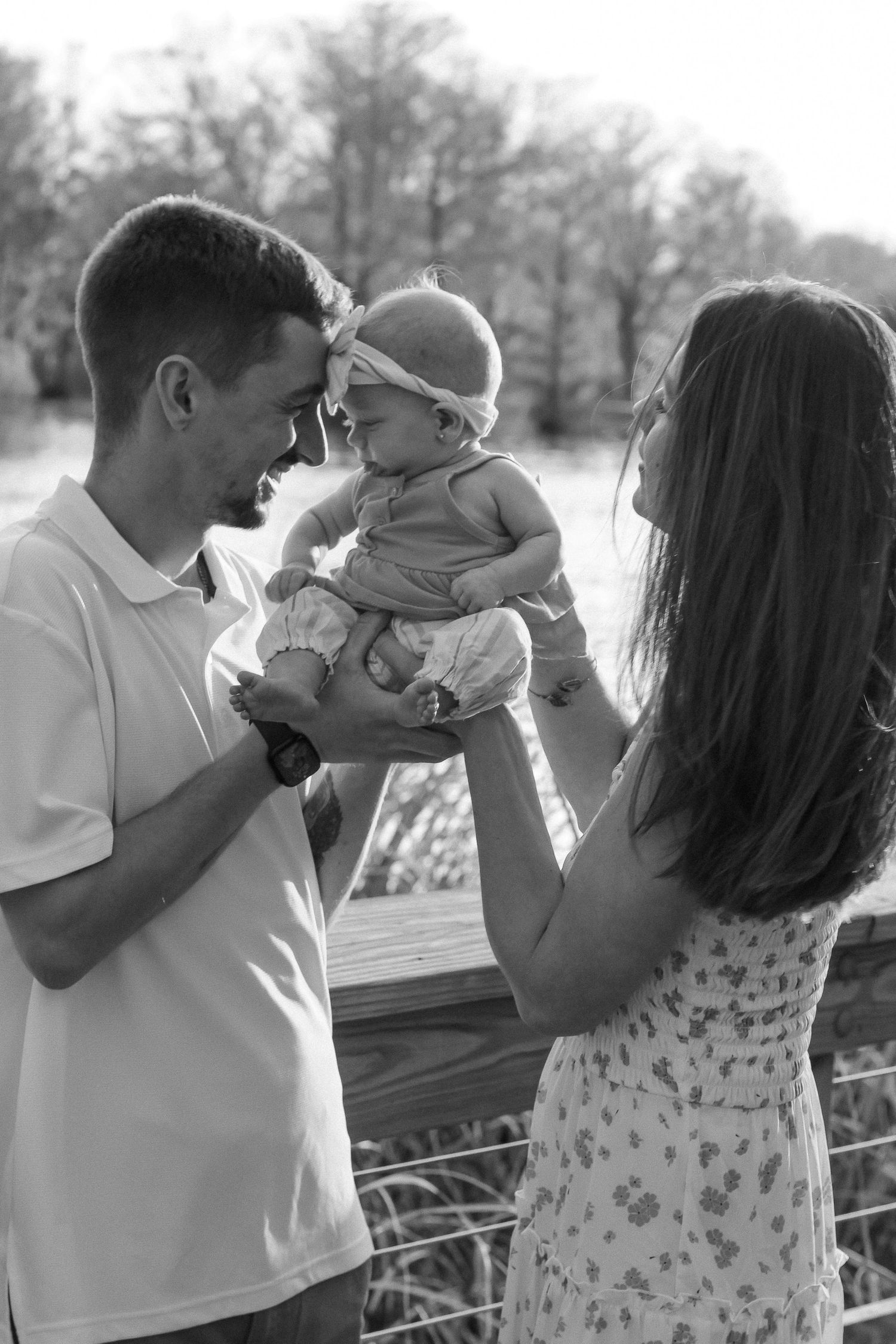 A joyful black and white family moment on a wooden deck overlooking water.