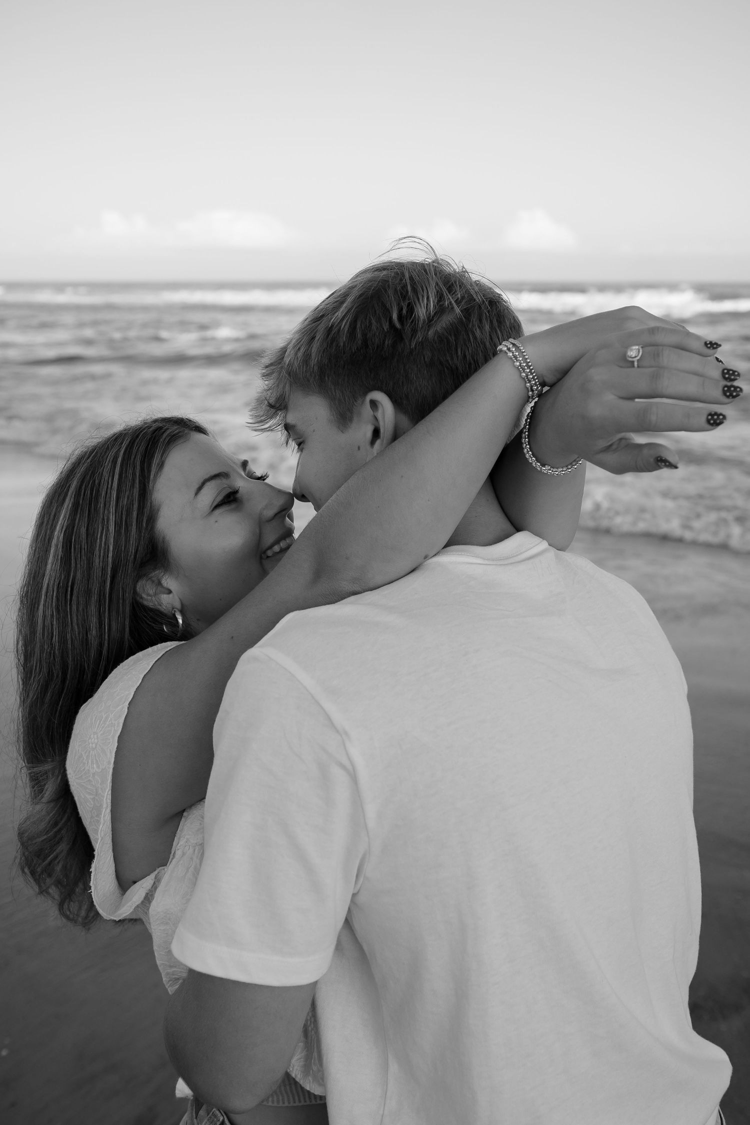 Romantic black and white beach portraits of a couple embracing.