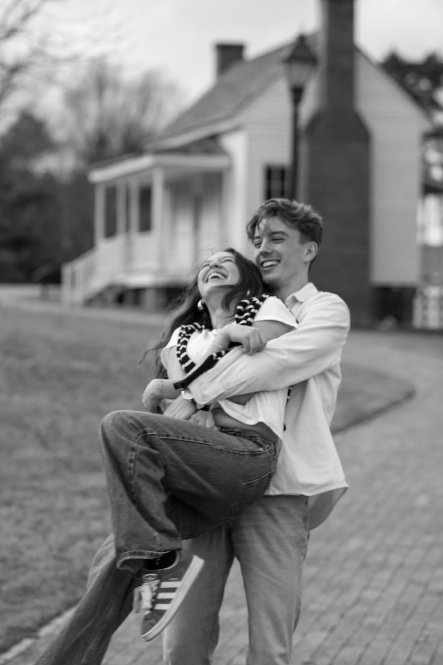 A joyful dancing moment captured in black and white on a brick pathway.