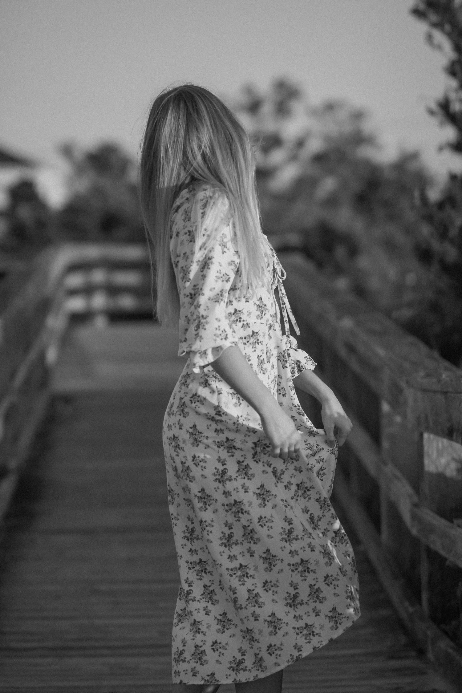 Black and white series showing movement in a floral dress on a wooden walkway.