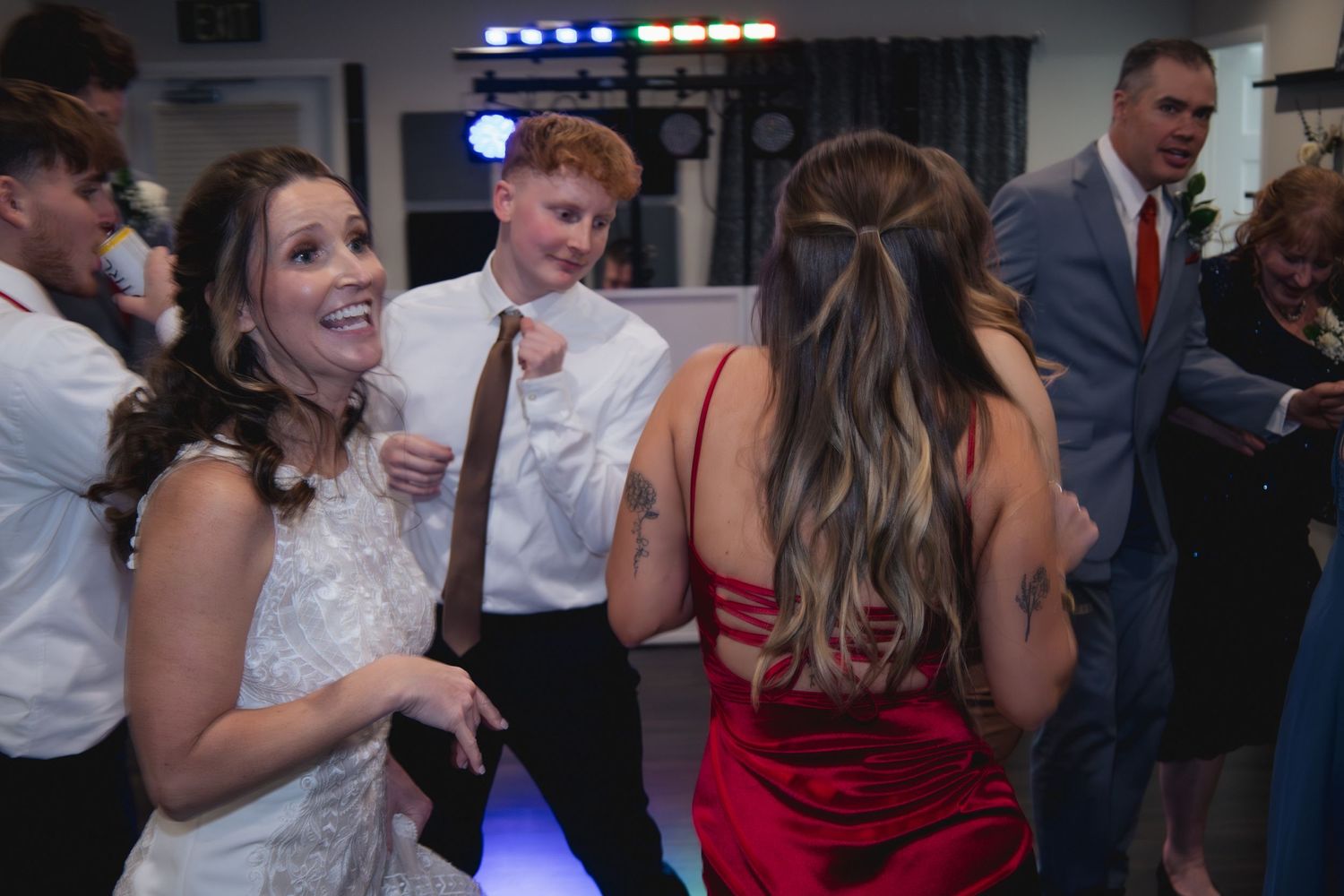Wedding reception dance party with colorful lighting and guests on dance floor.