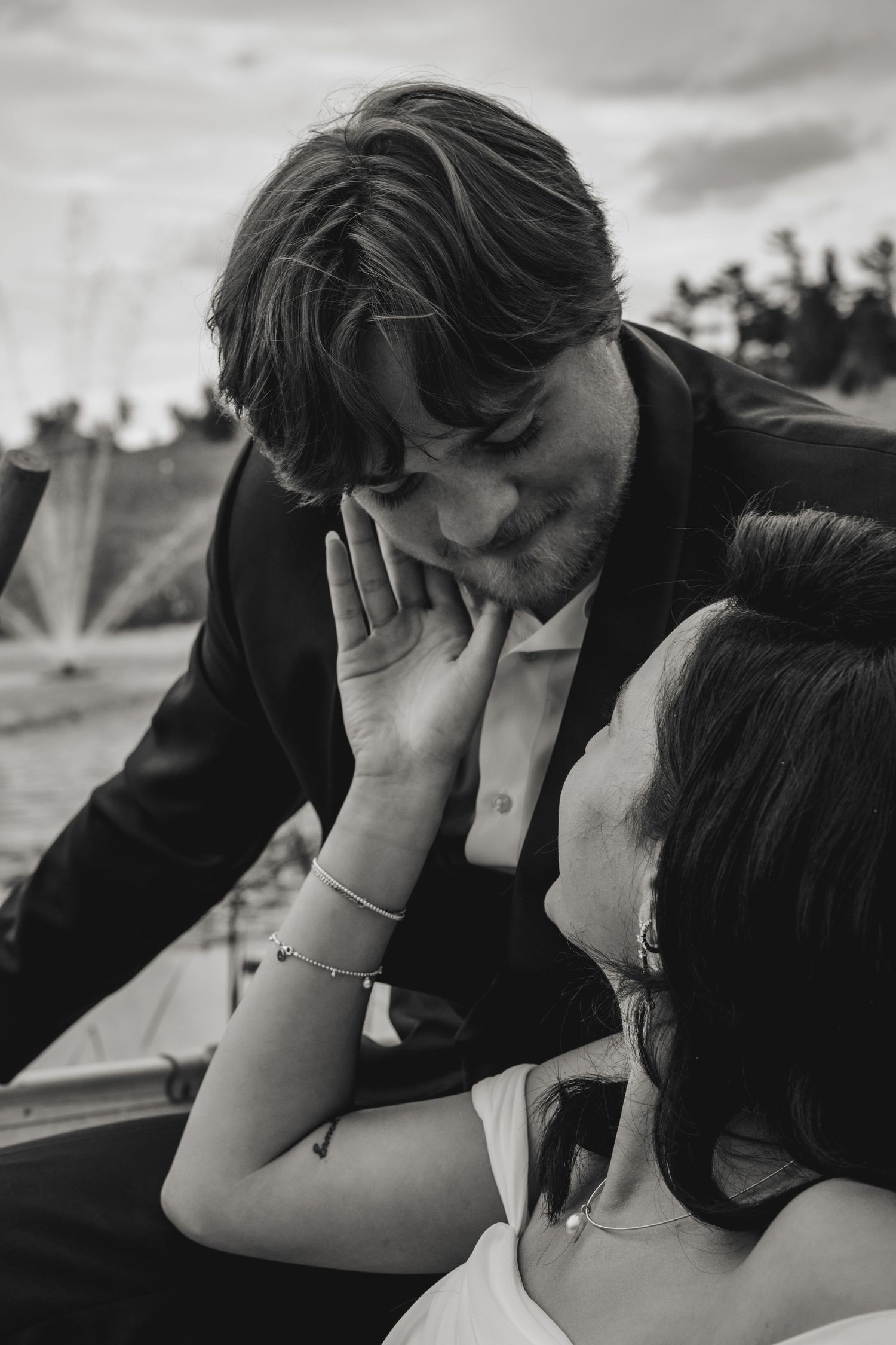 Black and white intimate wedding moment between couple as one lovingly cups the other's cheek during an outdoor photo session.