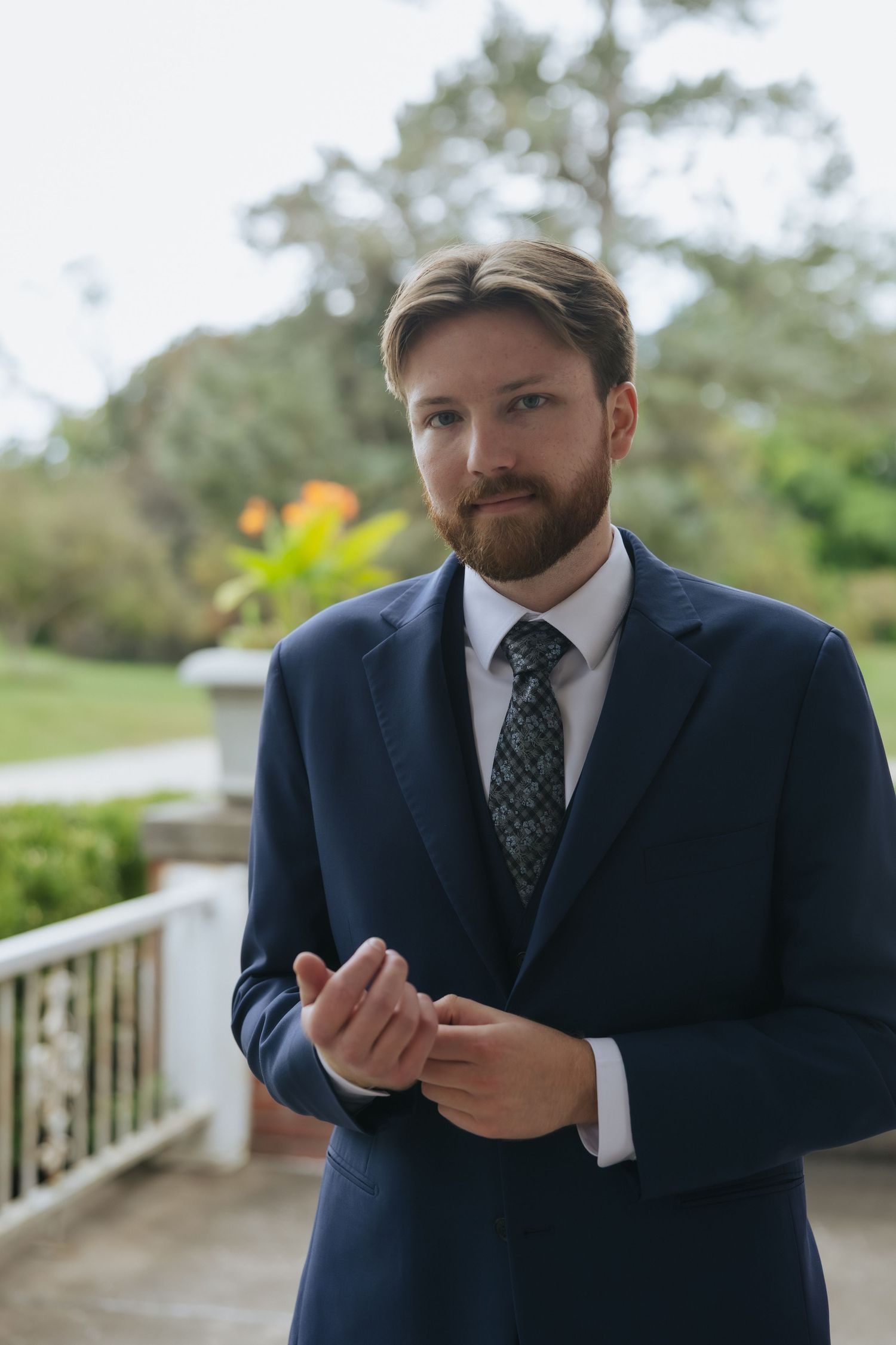 A person in a navy suit and polka dot tie gestures expressively in a series of outdoor photos.