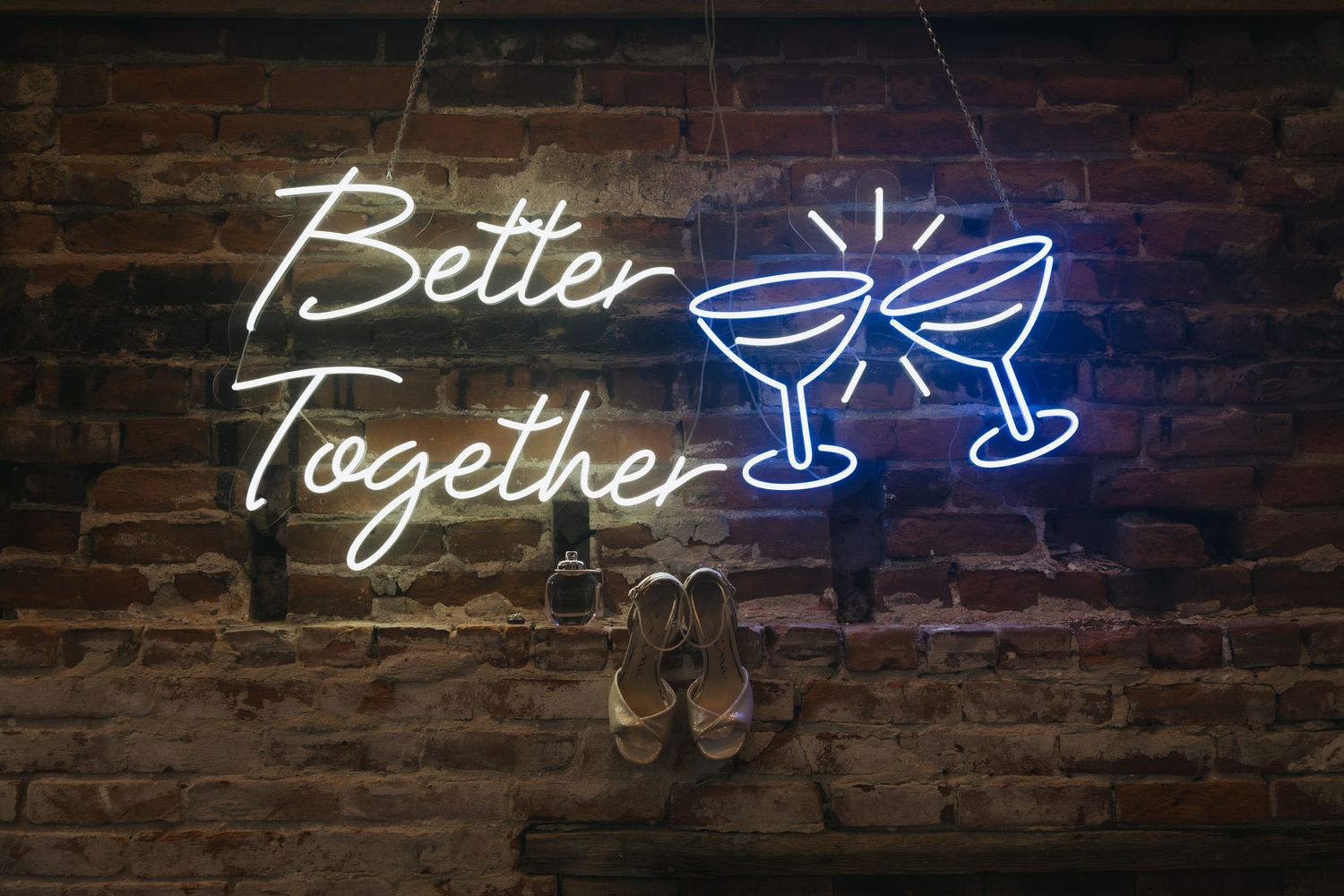 Four illuminated blue neon signs on brick walls displaying 'Better Together' with martini glass designs.