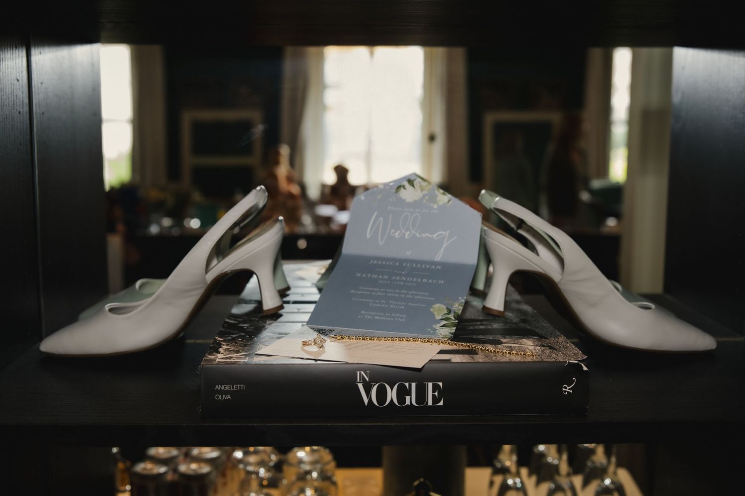 Wedding accessories including white high heels and a gray baseball cap arranged on top of a Vogue magazine.