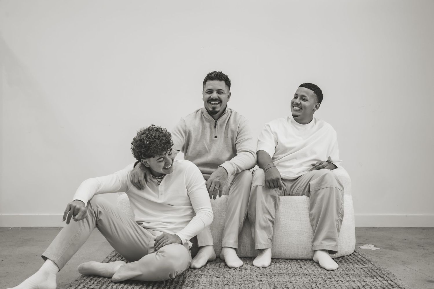 Two people sitting on floor wearing white shirts share joyful moments in black and white photo series.