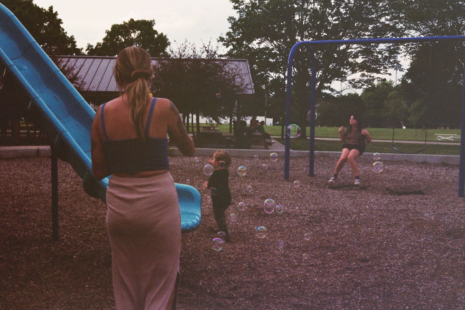 Three children enjoy playing together on a colorful playground slide during a sunny afternoon at the park.