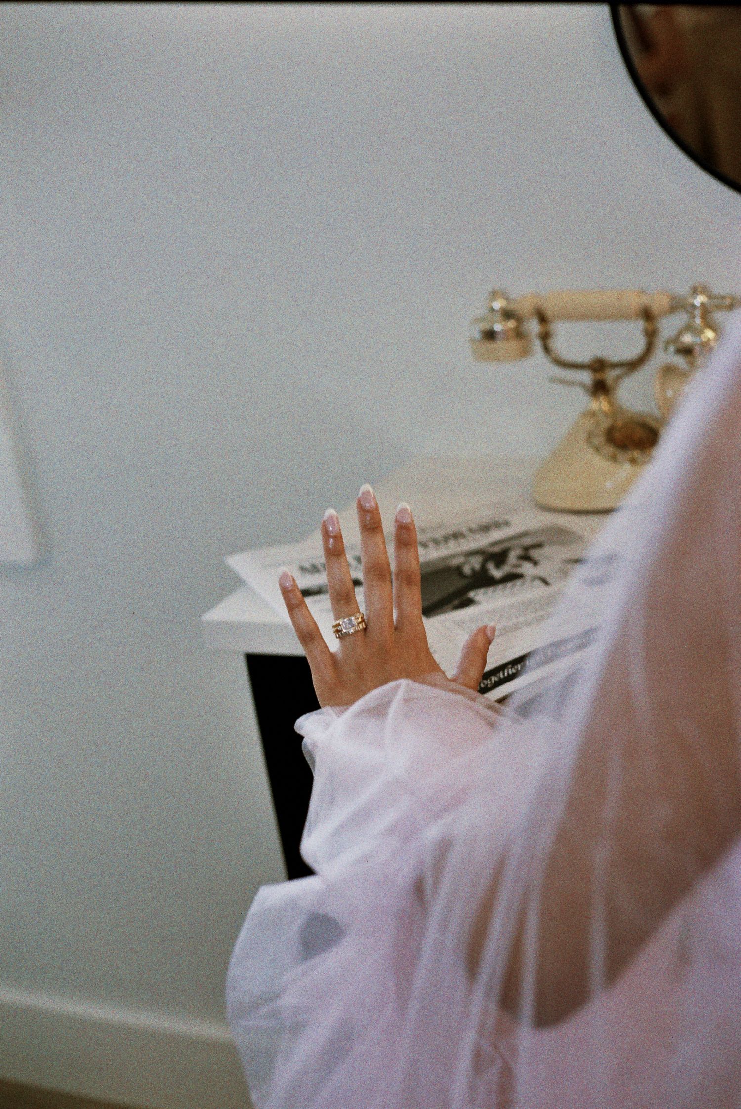 A hand wearing a white sleeve reaching up with a vintage rotary telephone visible in the background.