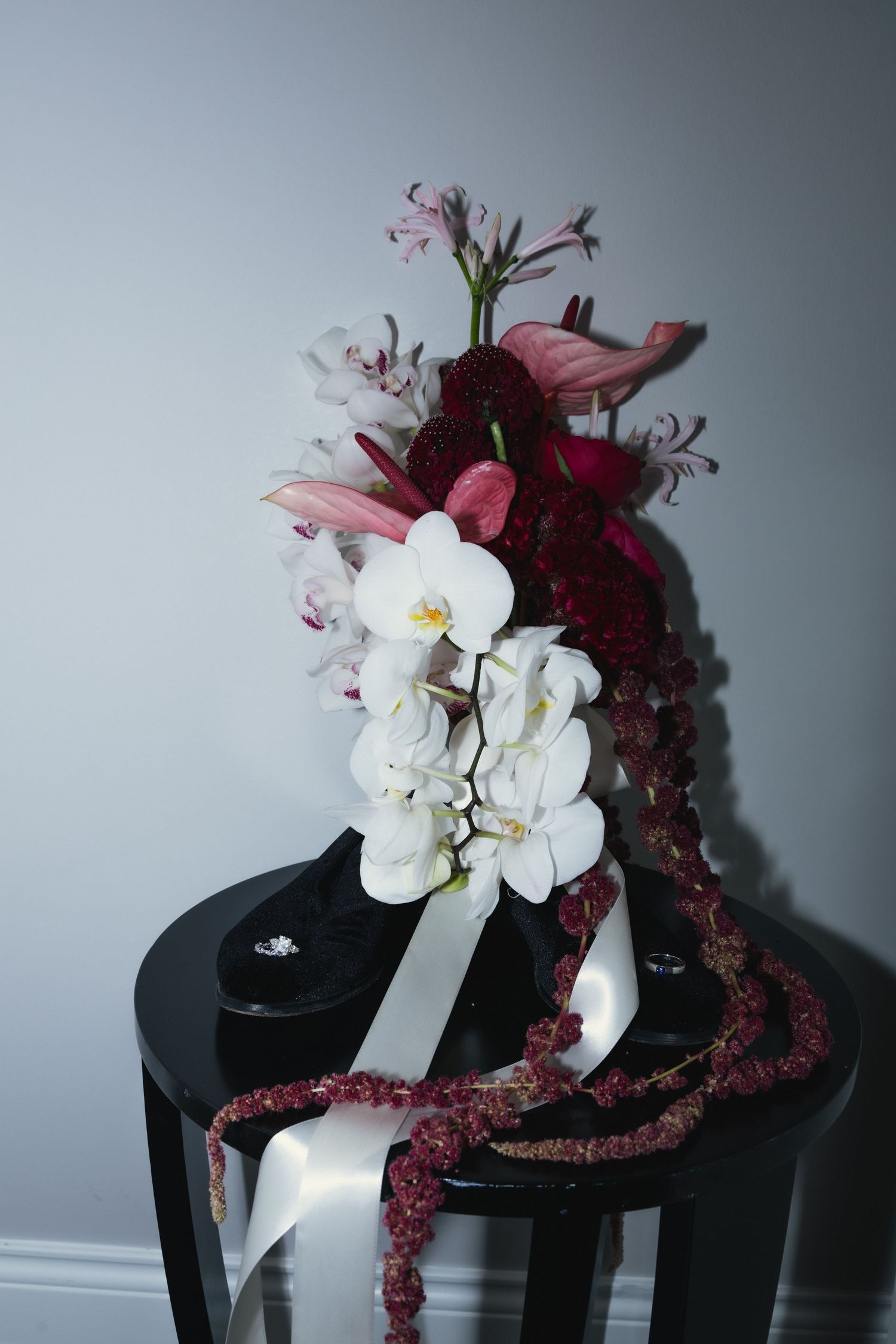 A black hat adorned with white orchids and deep burgundy flowers creates an elegant and dramatic arrangement.