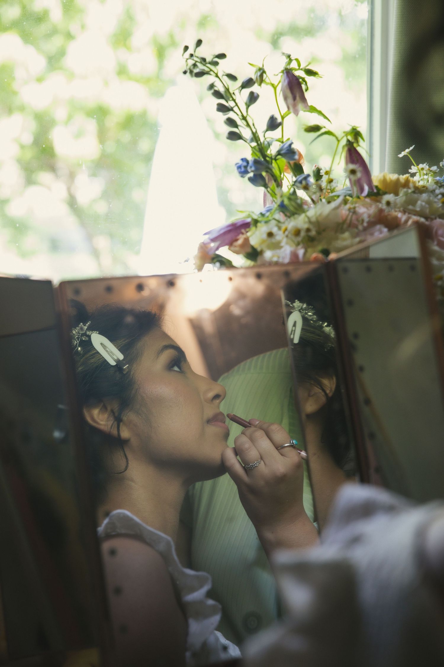 A soft artistic photo series captures someone looking upwards with delicate flowers and foliage in their hair.