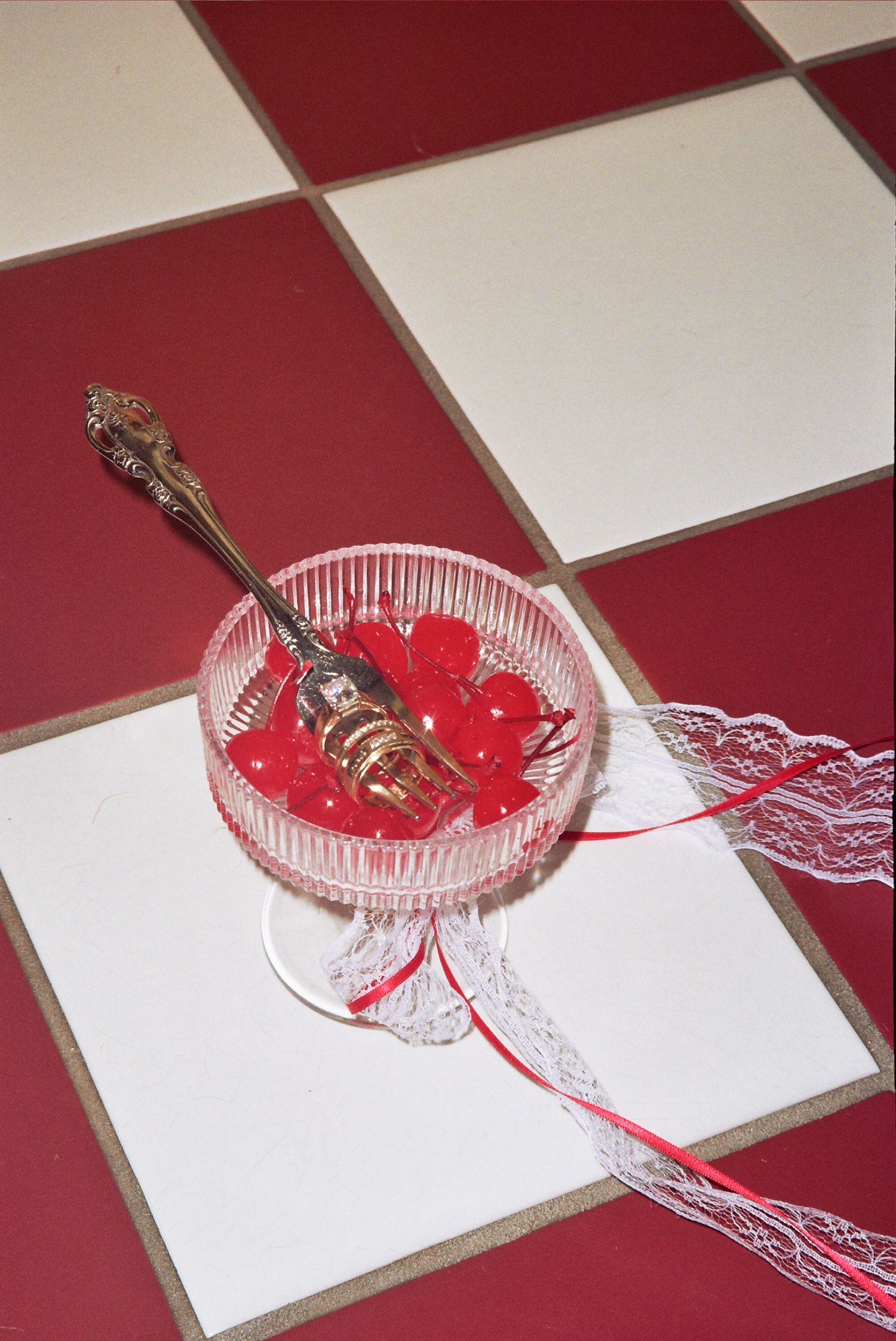 Clear glass dish with red lace trim and decorative spoon shown from multiple angles on a red and white checkered surface.
