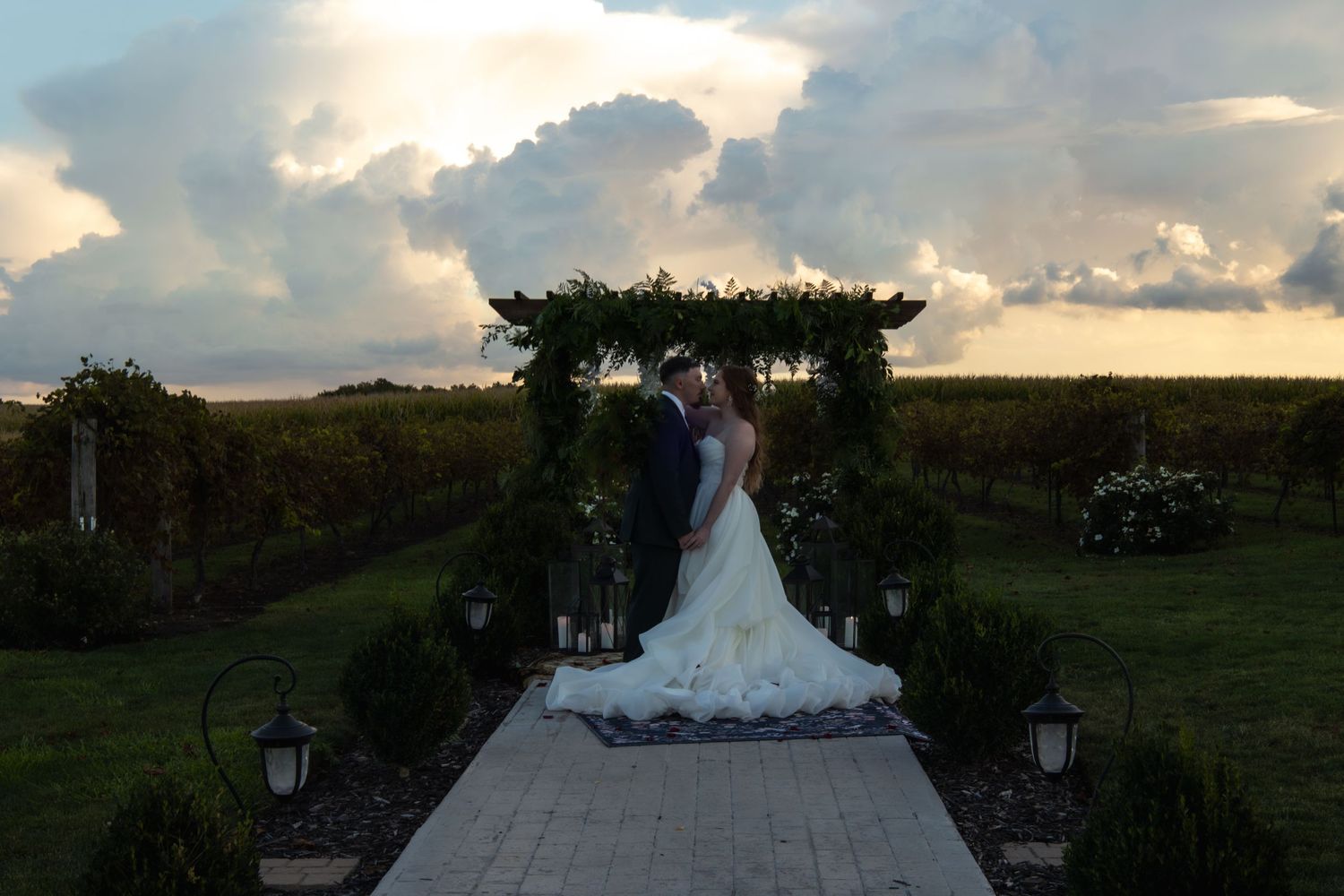 A couple shares an intimate moment under an arch at sunset on their wedding day.