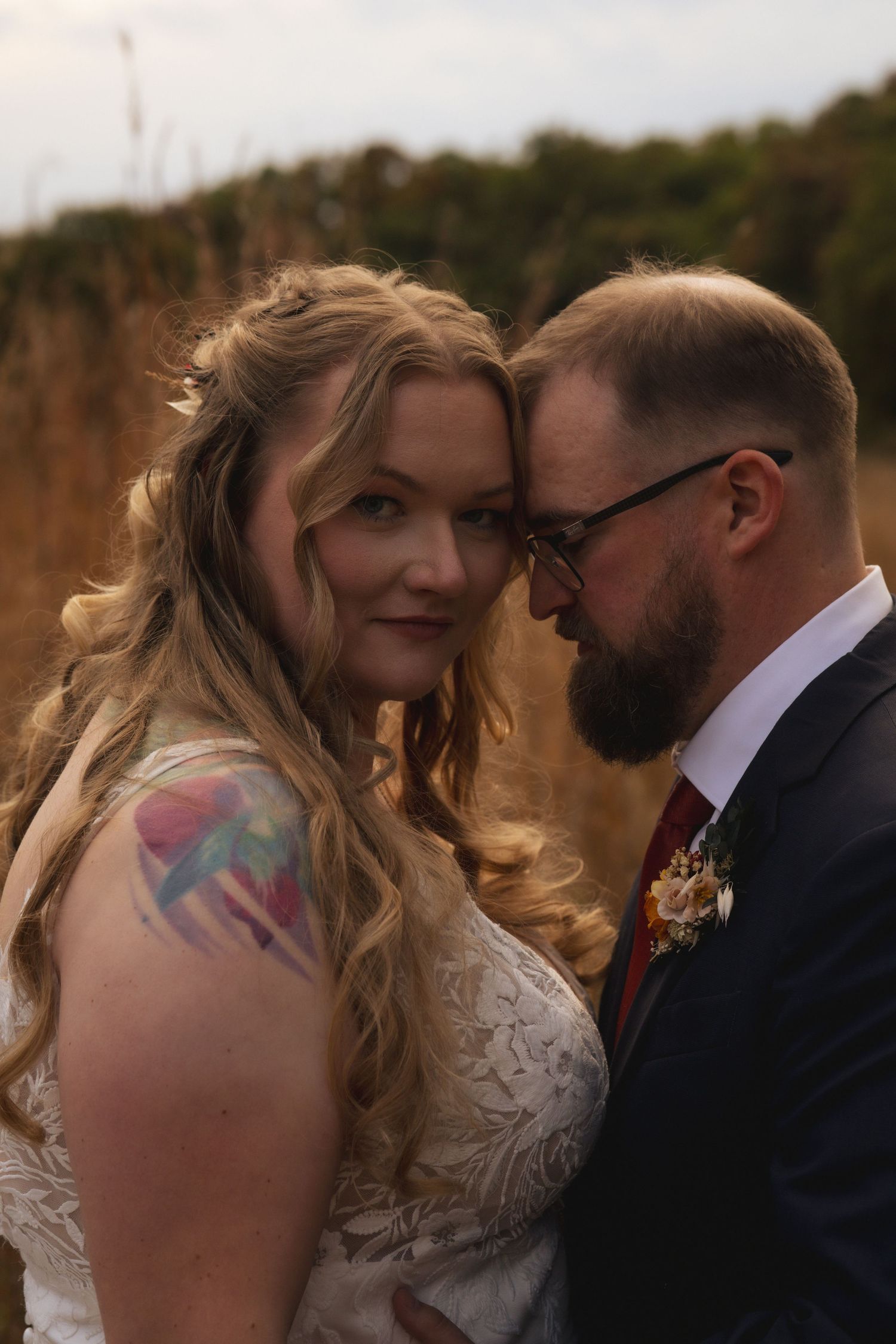 Romantic outdoor wedding portrait with couple sharing an intimate moment at sunset.