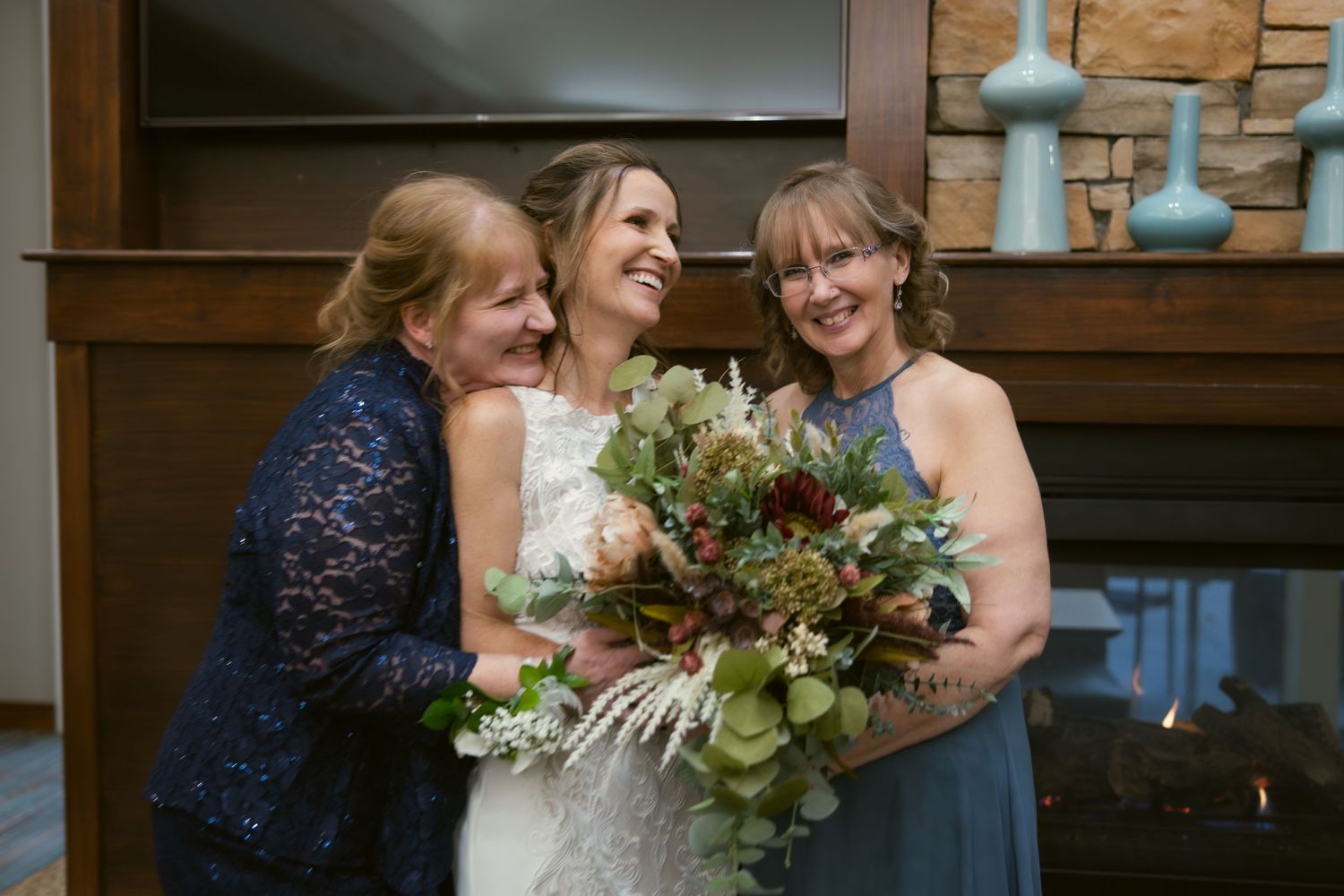 Three people sharing joyful moment with wedding bouquet against wooden background.