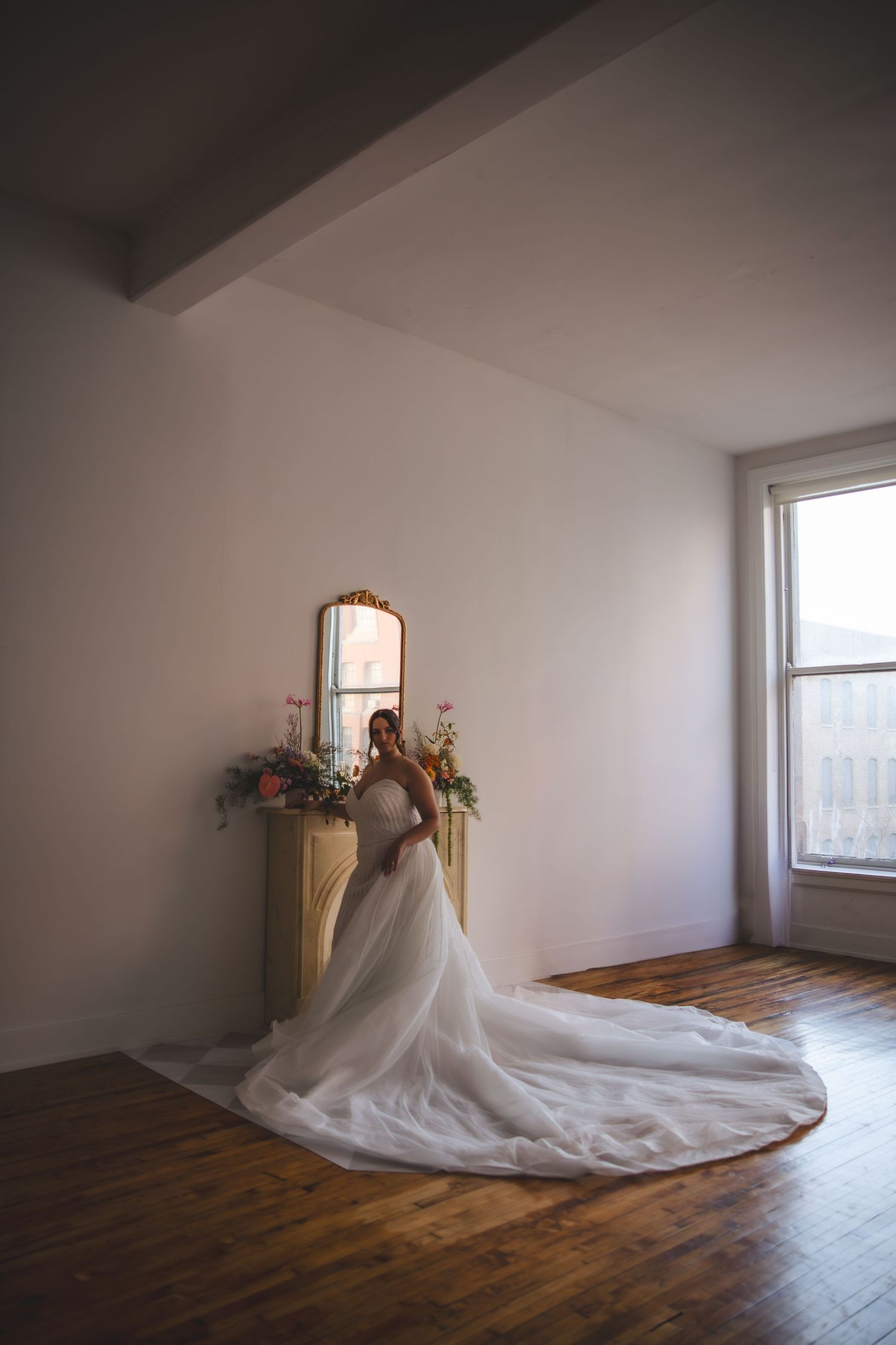 A wedding gown with a flowing train photographed in a minimalist room with natural light.