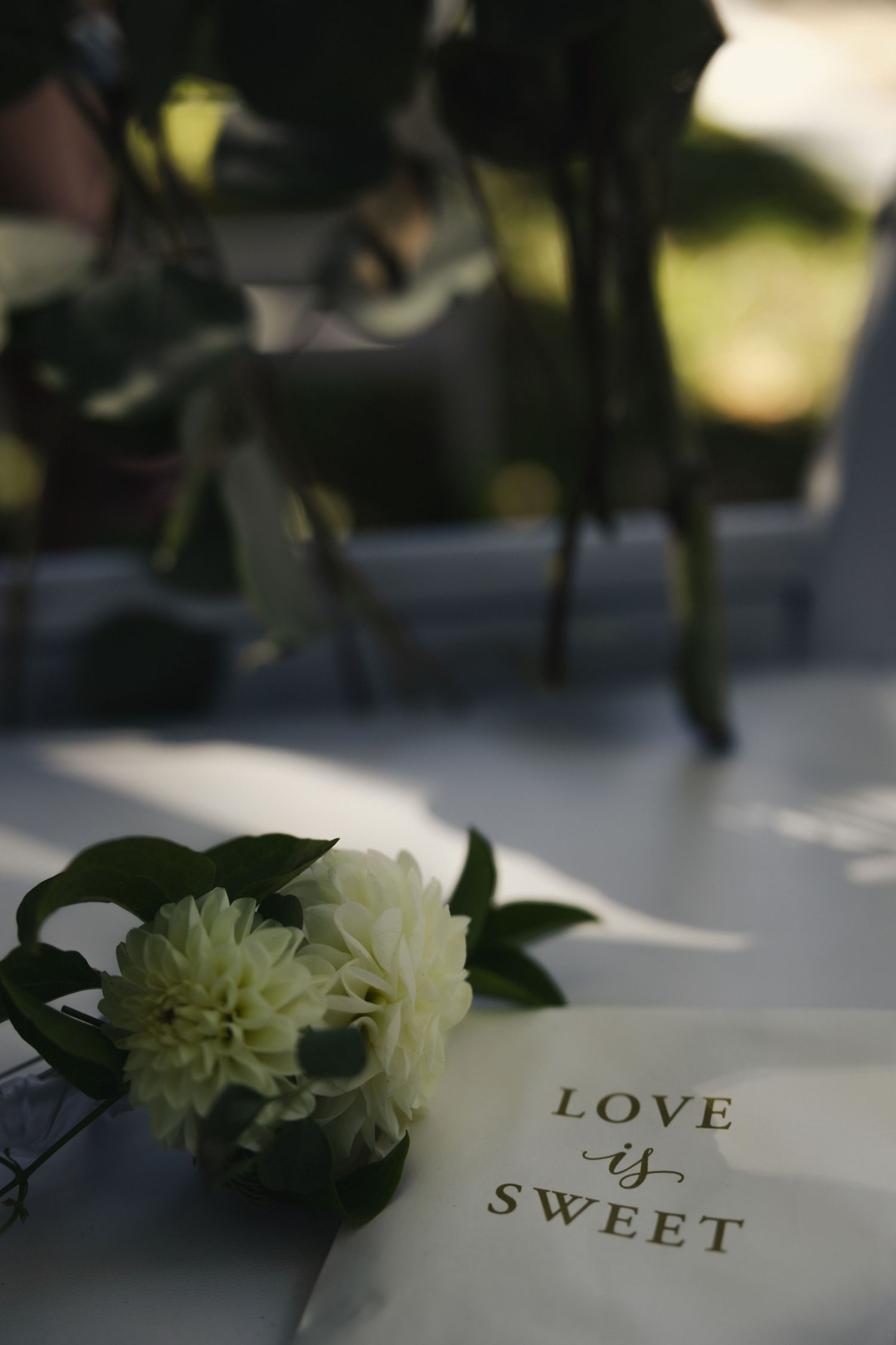 White flowers and text reading 'LOVE' and 'SWEET' create an elegant wedding decor arrangement with soft lighting.