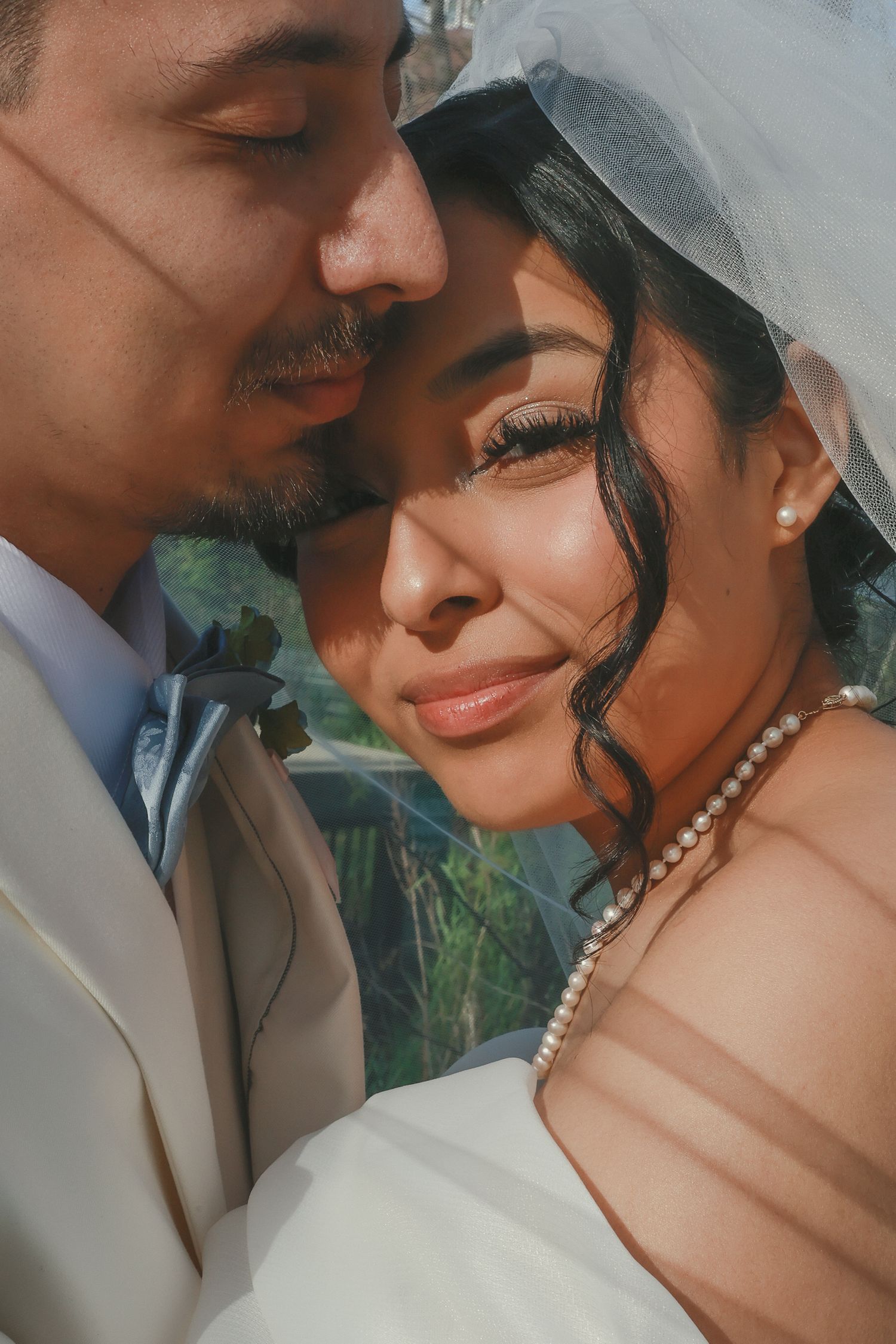 Five romantic close-up photos of a couple in wedding attire sharing intimate moments together on their special day.