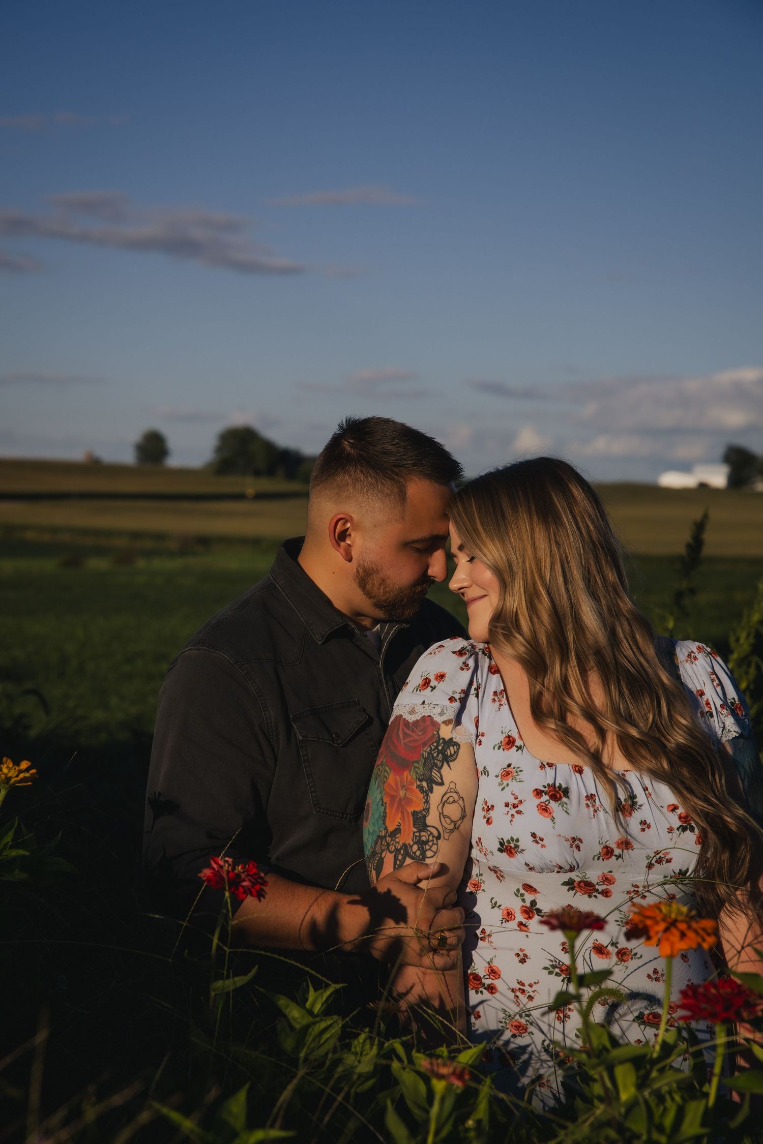 A couple embraces in a romantic series of sunset photos in a rural field with vibrant wildflowers at golden hour.