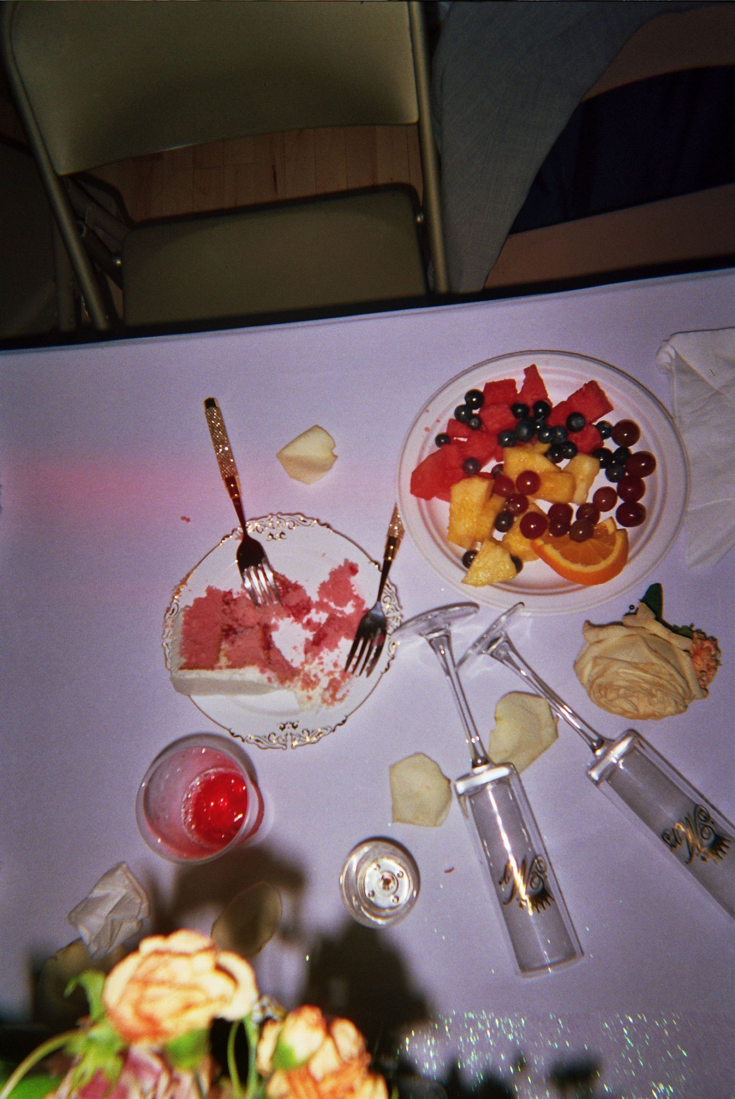 Overhead view of colorful fruit platters with watermelon, mixed berries, and cocktail glasses on a white surface.