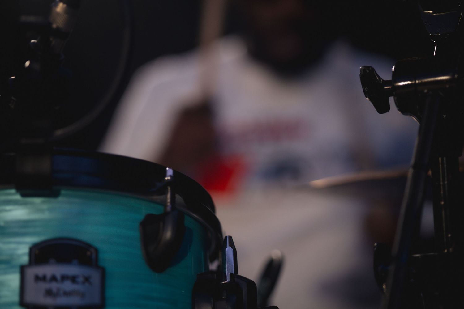 Close-up shot of a drum kit with microphones in dim lighting shows musical equipment setup.