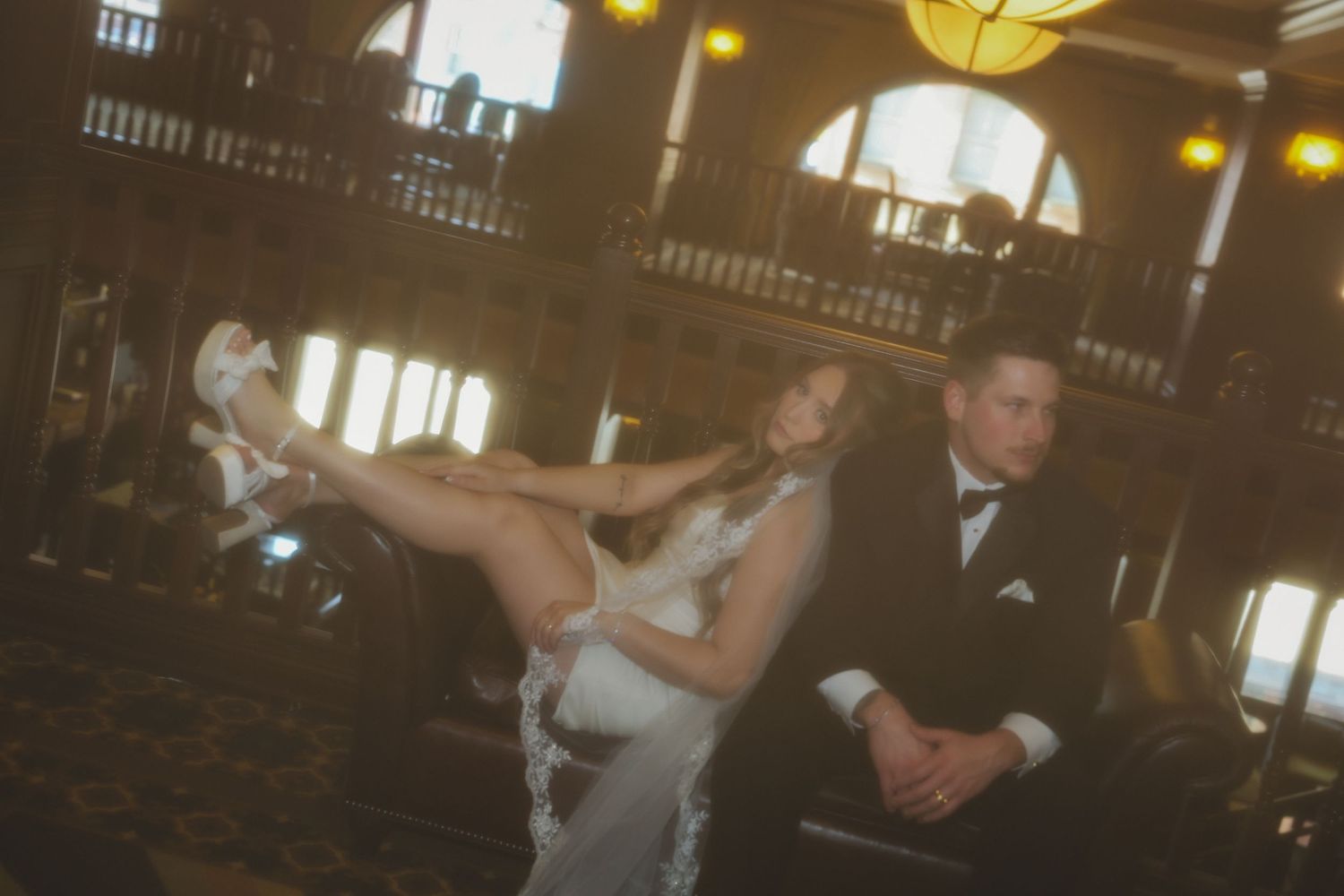 Couple performs a dramatic dance move in elegant evening attire at an ornate venue with warm lighting.