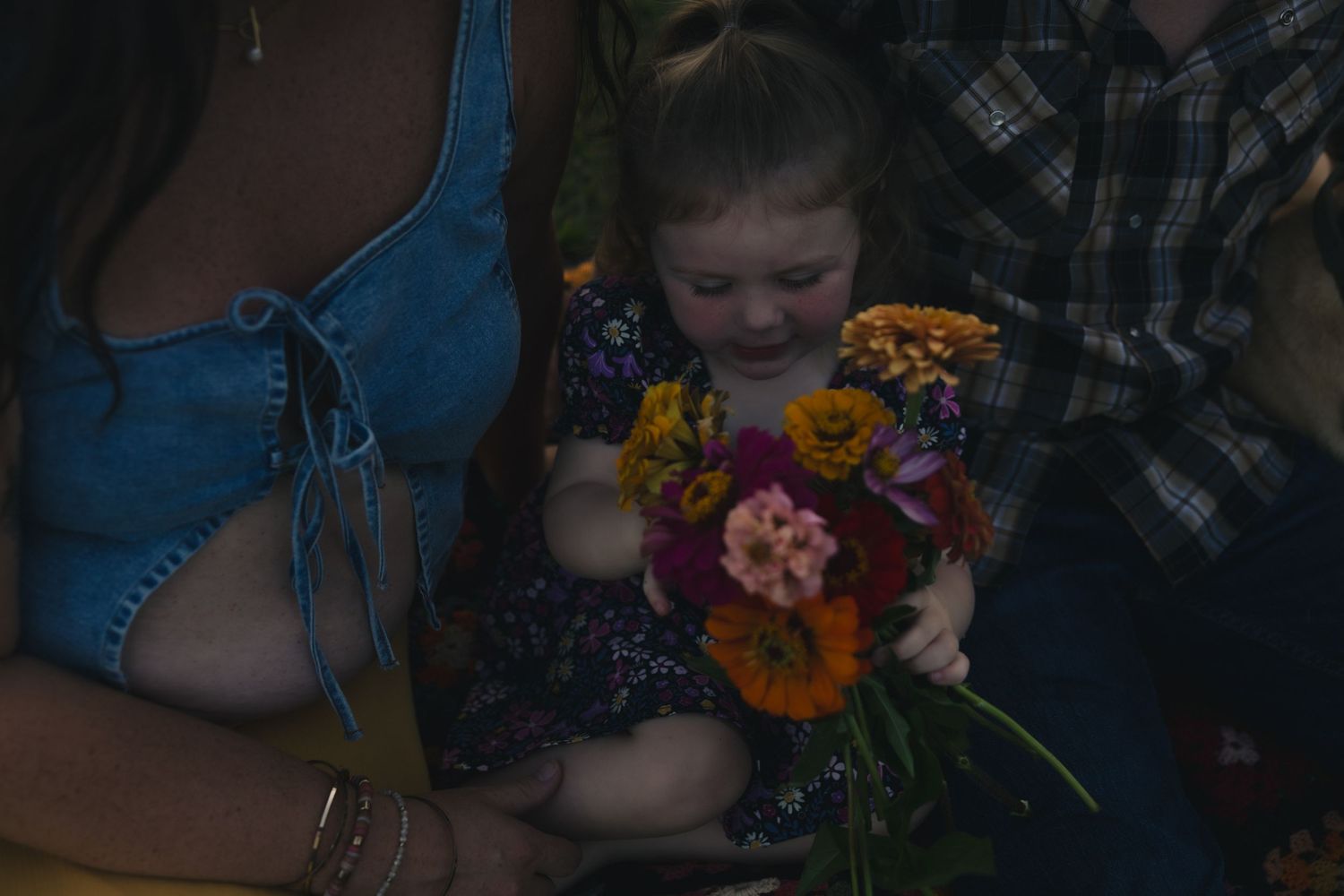 A sequence of photos shows a young child smelling and enjoying colorful flowers in a dark setting.