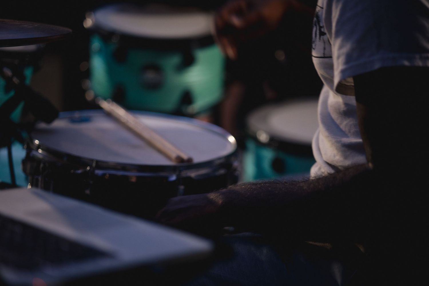 Close-up view of a snare drum and drumsticks in a dimly lit performance setting.