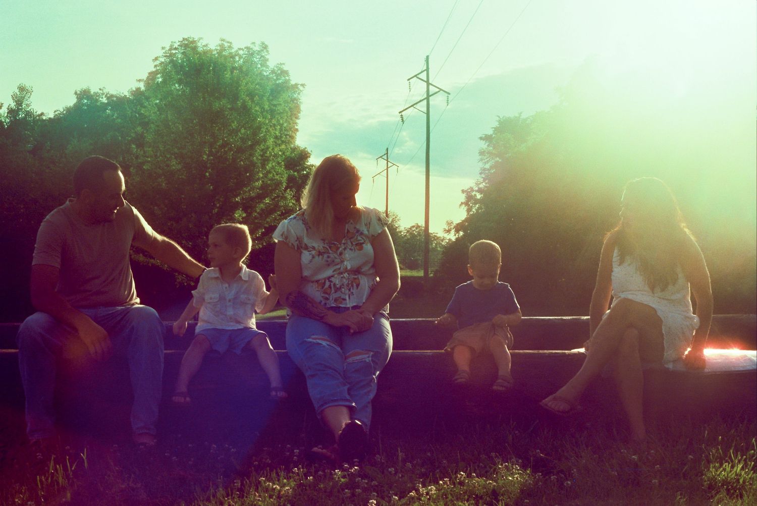 Group of people silhouetted against a warm sunset sky during a summer gathering outdoors.