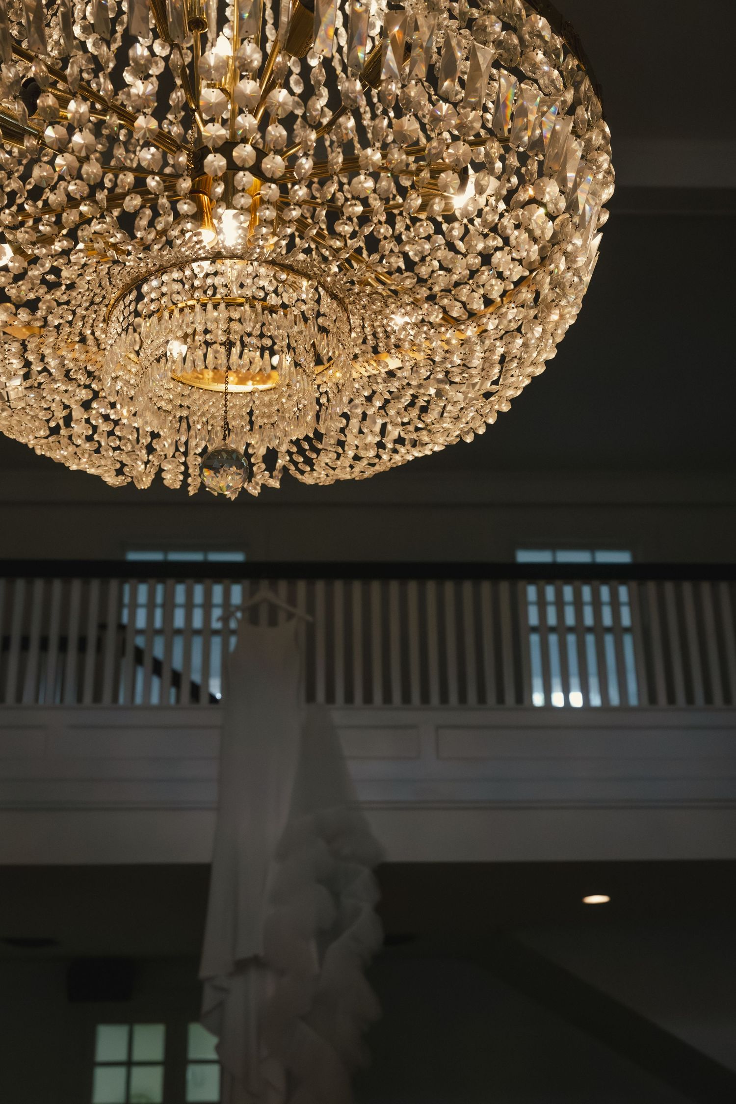 Elegant crystal chandelier with cascading tiers of glass beads illuminates a dark interior space.
