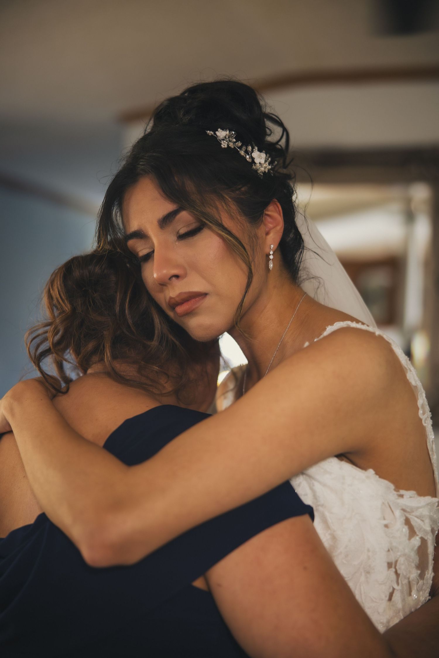 A heartfelt embrace between a person wearing a white wedding dress and someone in a navy suit.