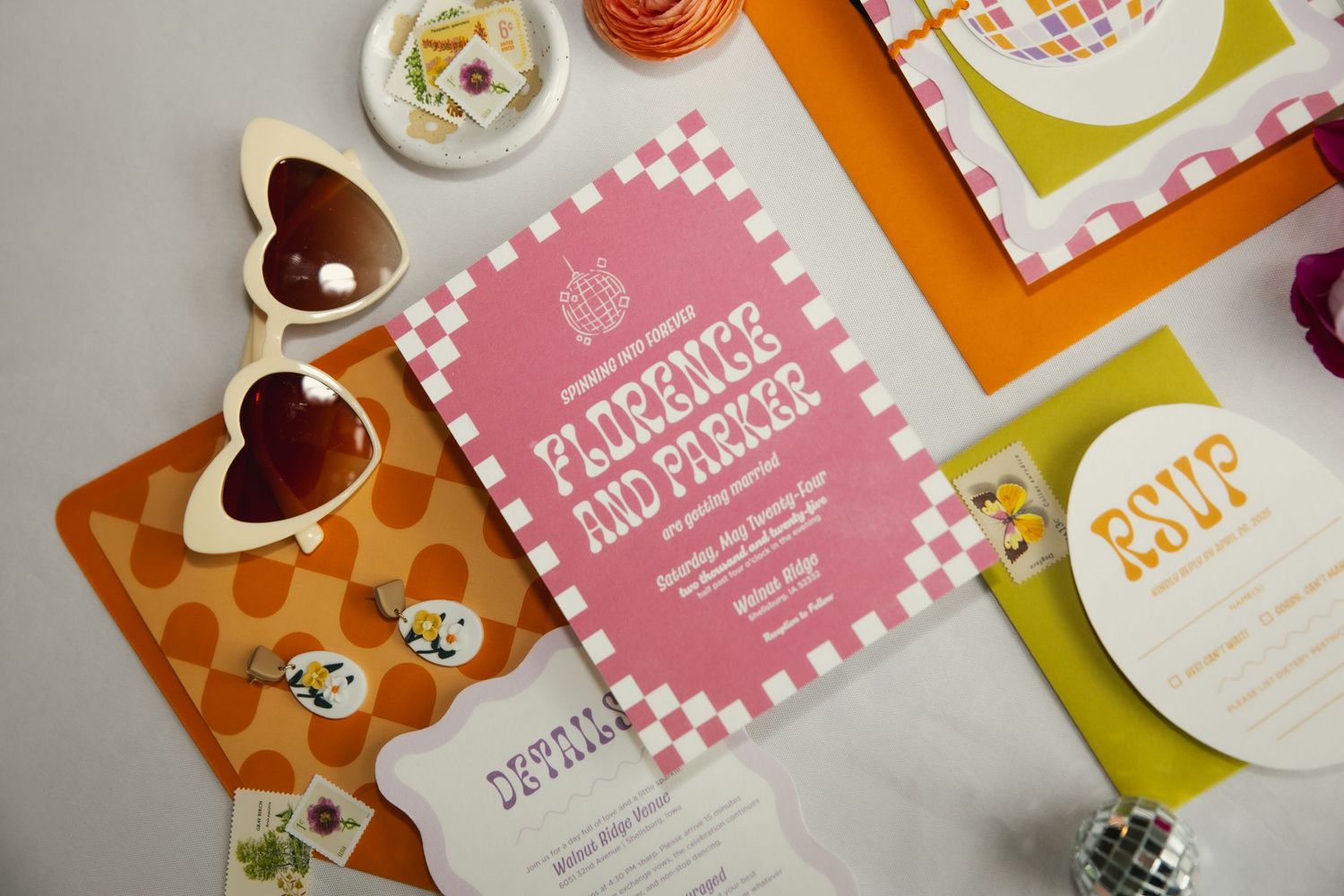 A collection of colorful wedding stationery including invites and heart-shaped dishes laid out on a white surface.
