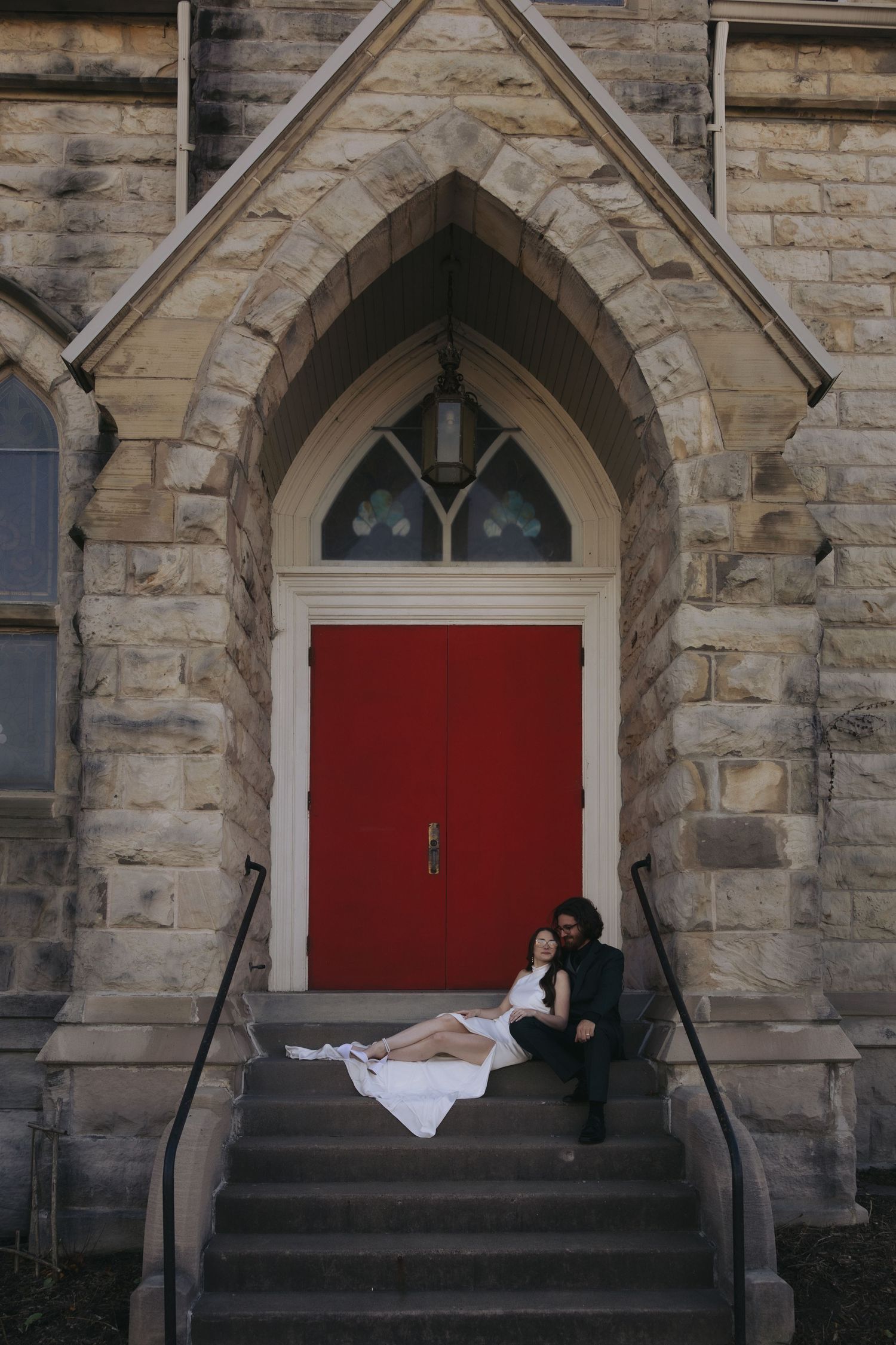 A series of four photos showing a couple in wedding attire posing on stone church steps with red doors.