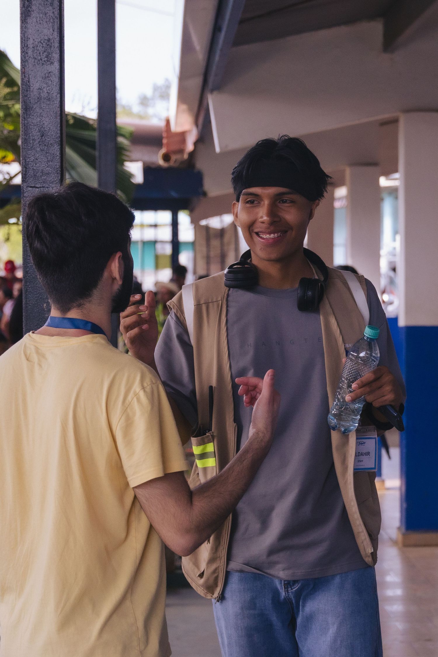Two students having a friendly conversation in a covered walkway while holding water bottles.