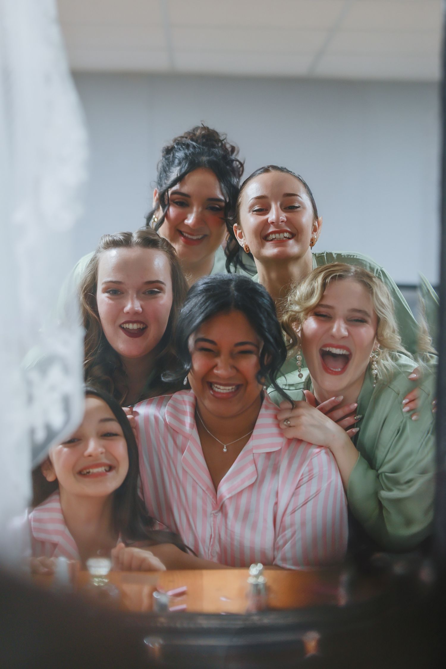 A group of diverse friends in sleepwear laugh and smile together during what appears to be a casual gathering.