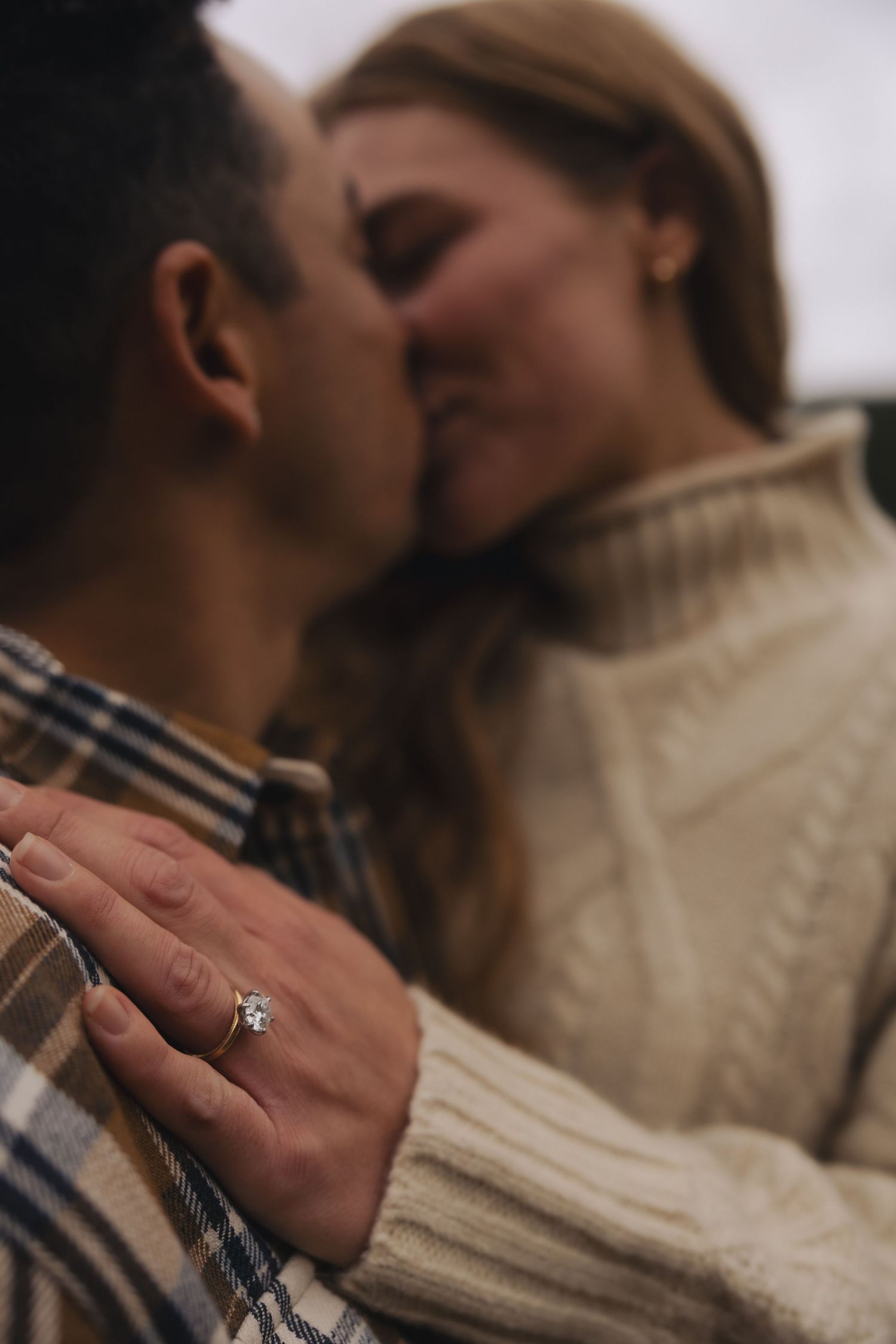 A romantic engagement photo series showing close-up shots of a couple kissing while displaying a diamond ring.