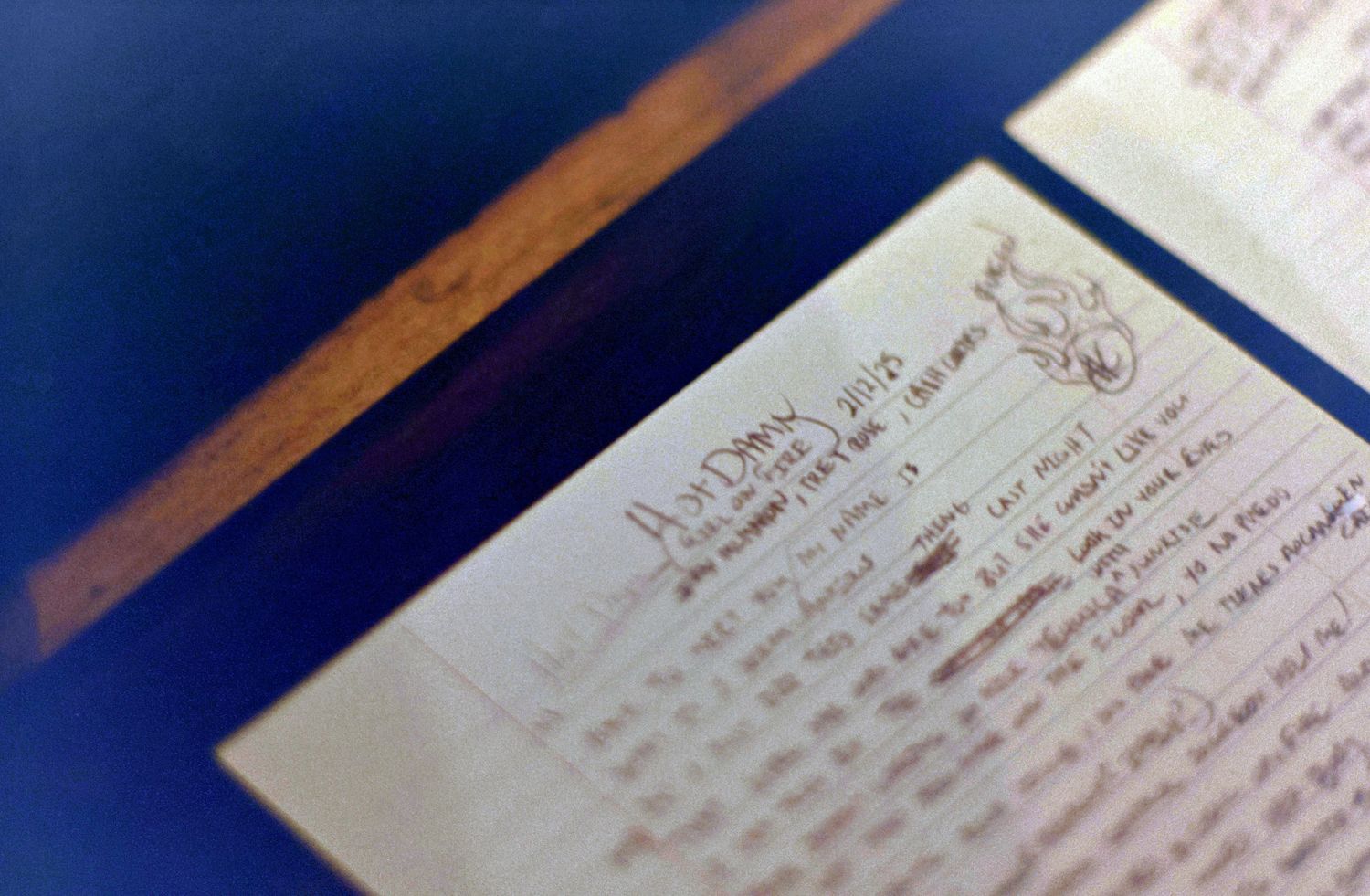 Close-up of a handwritten letter on aged paper with decorative header, displayed on a blue surface.