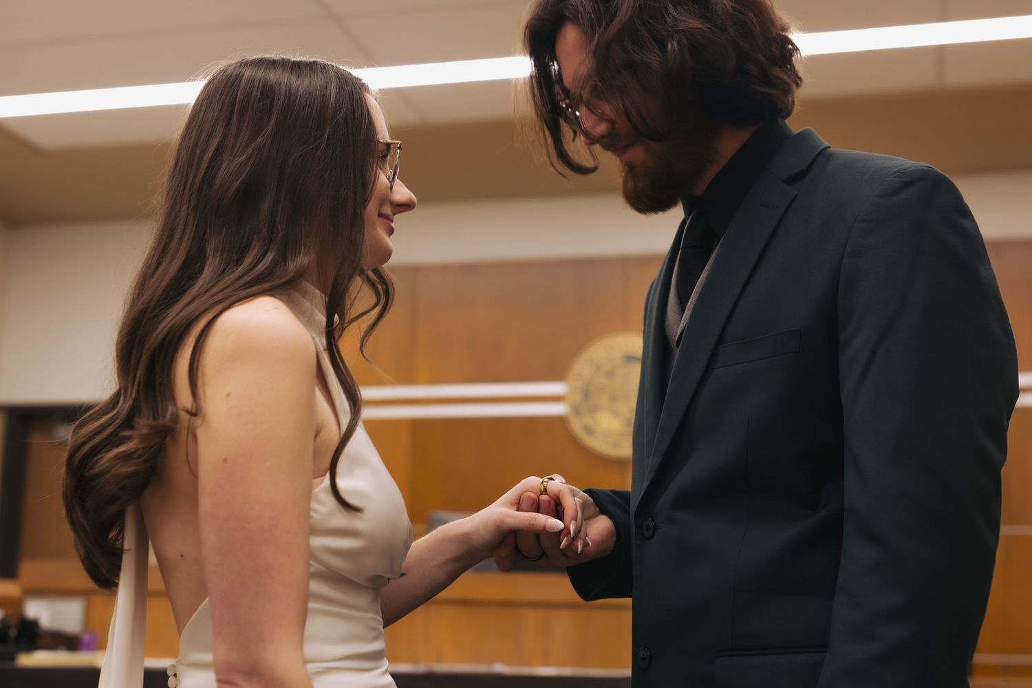 A couple shares an intimate moment together in formal attire, with the woman holding something in her hand.