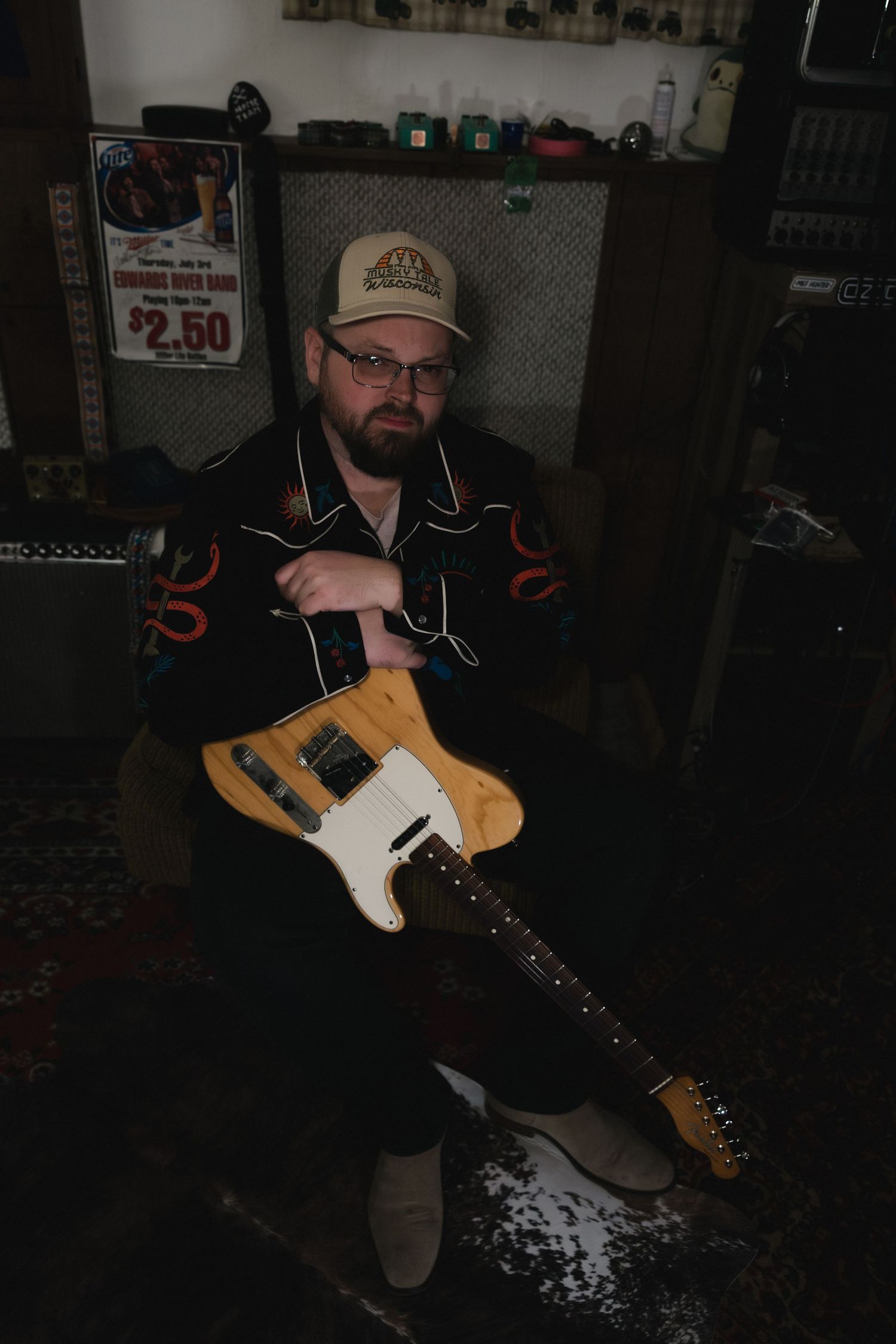 Guitar player in dark room holds a yellow Telecaster-style electric guitar.