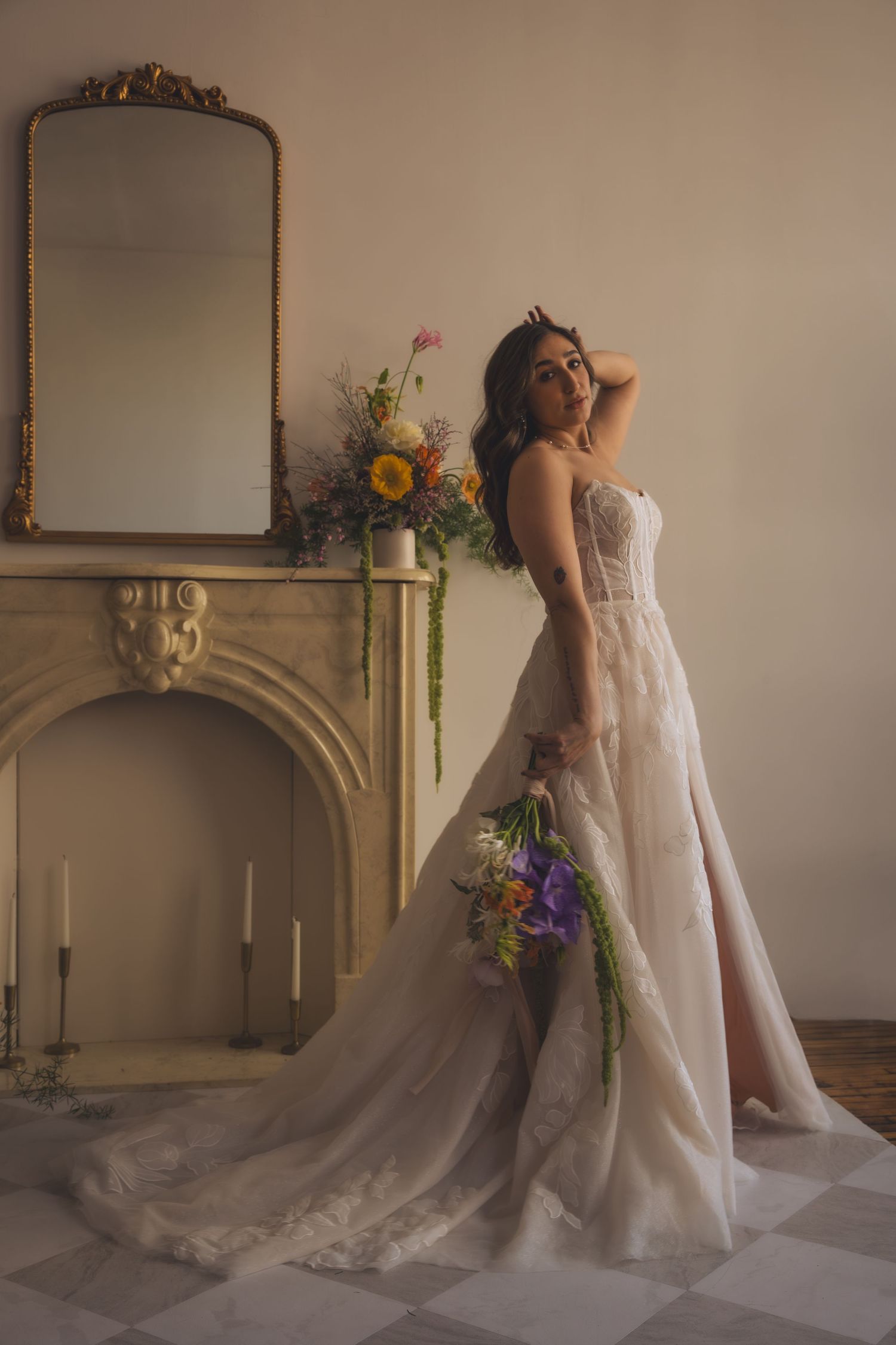 Romantic bridal portrait featuring an ornate mirror, floral arrangements, and a flowing white wedding gown with train.