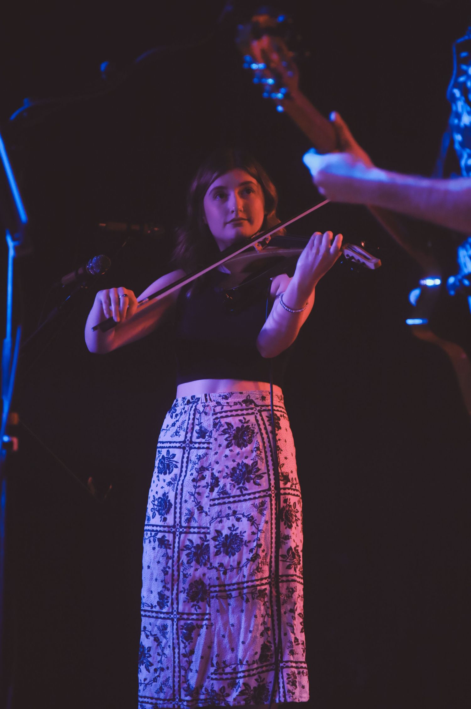 Performer in a patterned dress under dramatic blue stage lighting during live performance.