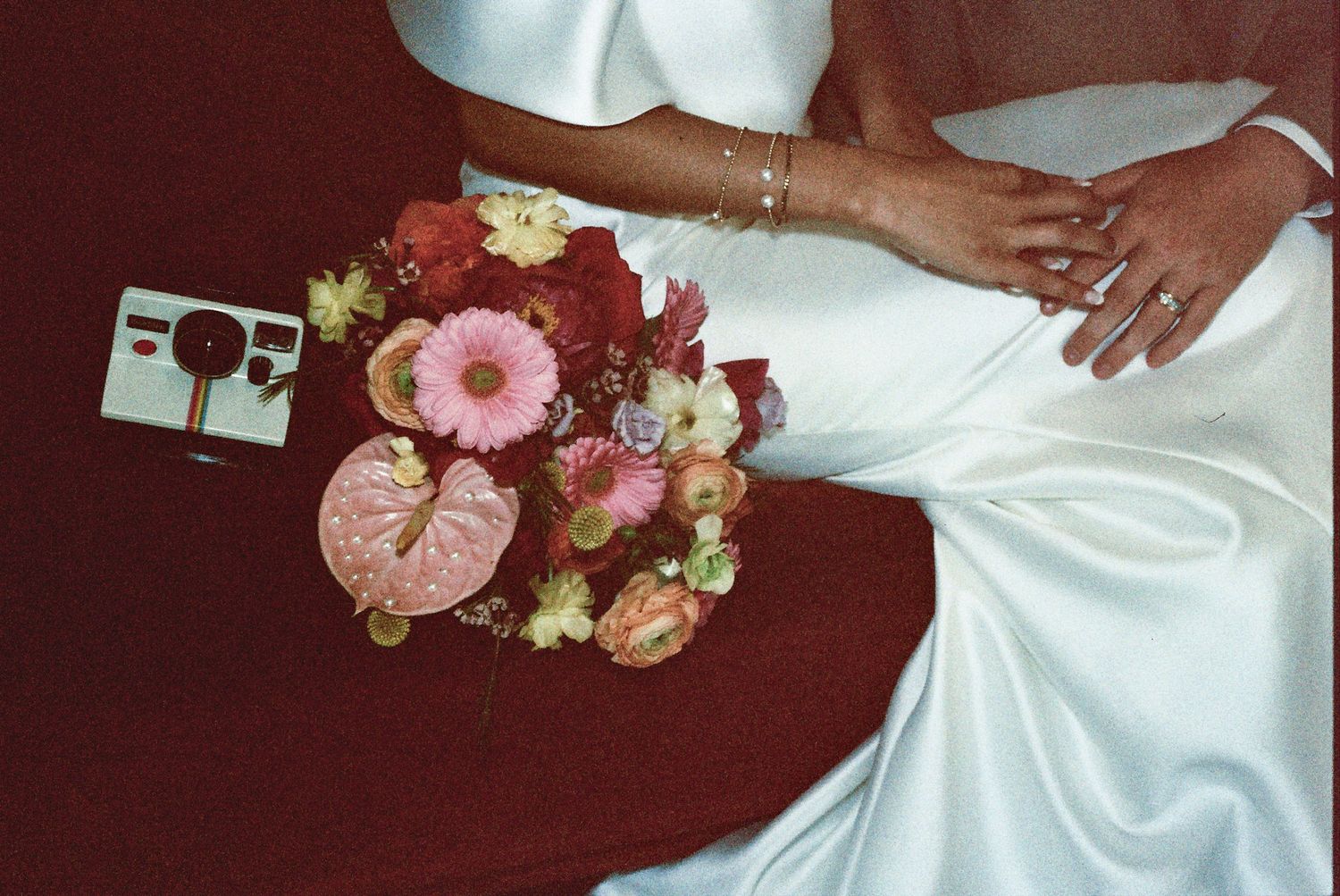 A close-up of pink and burgundy floral arrangements adorning a white dress, creating an elegant wedding detail.