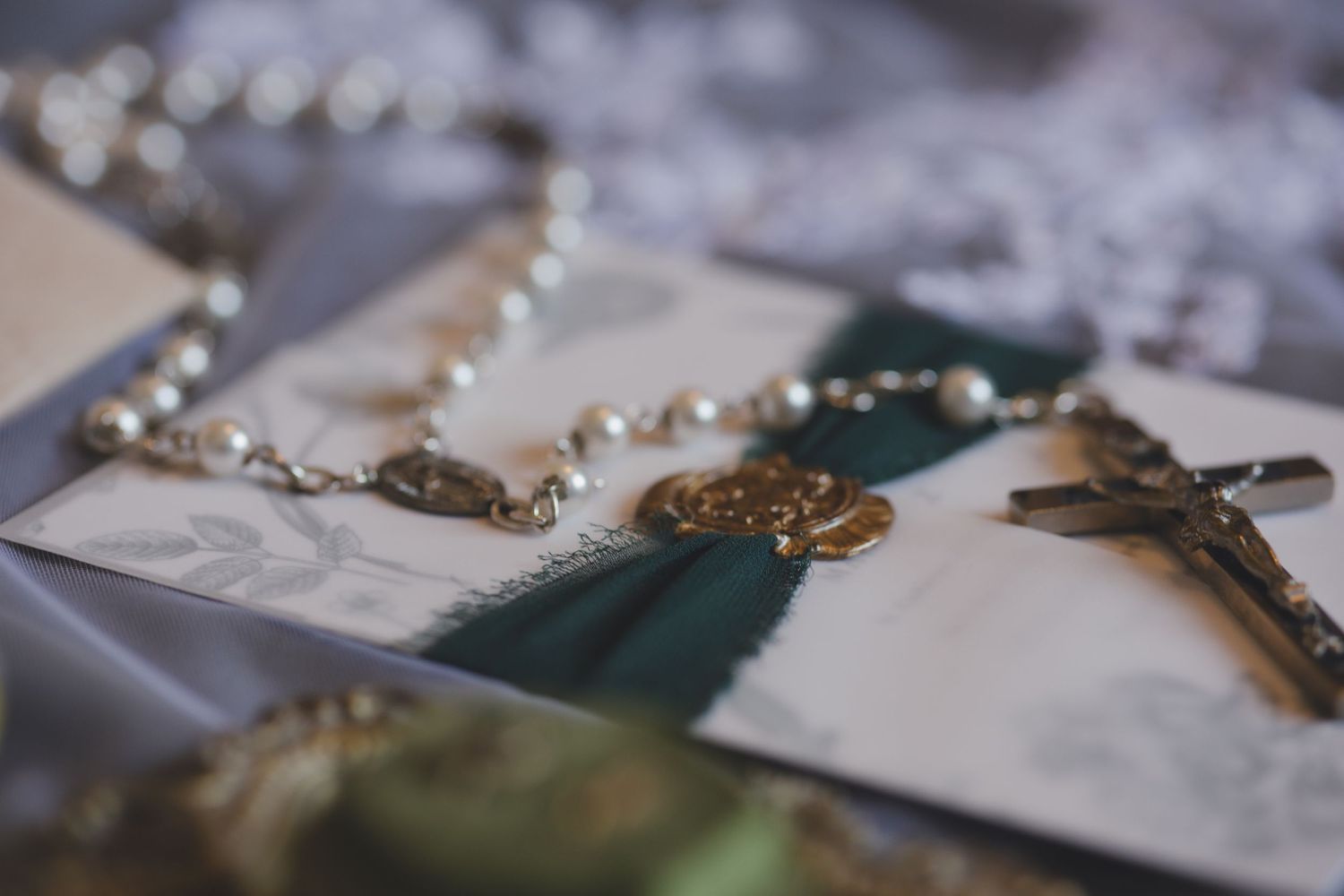 Pearl beaded necklace displayed on scattered photographs with soft bokeh effect and teal accents.