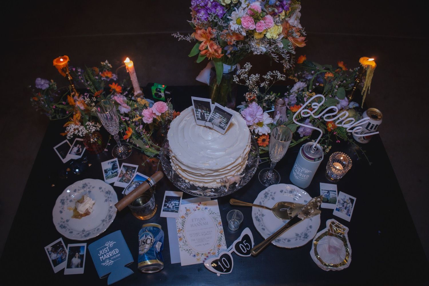 Wedding reception table decorated with colorful flowers, candles, photos and place settings.