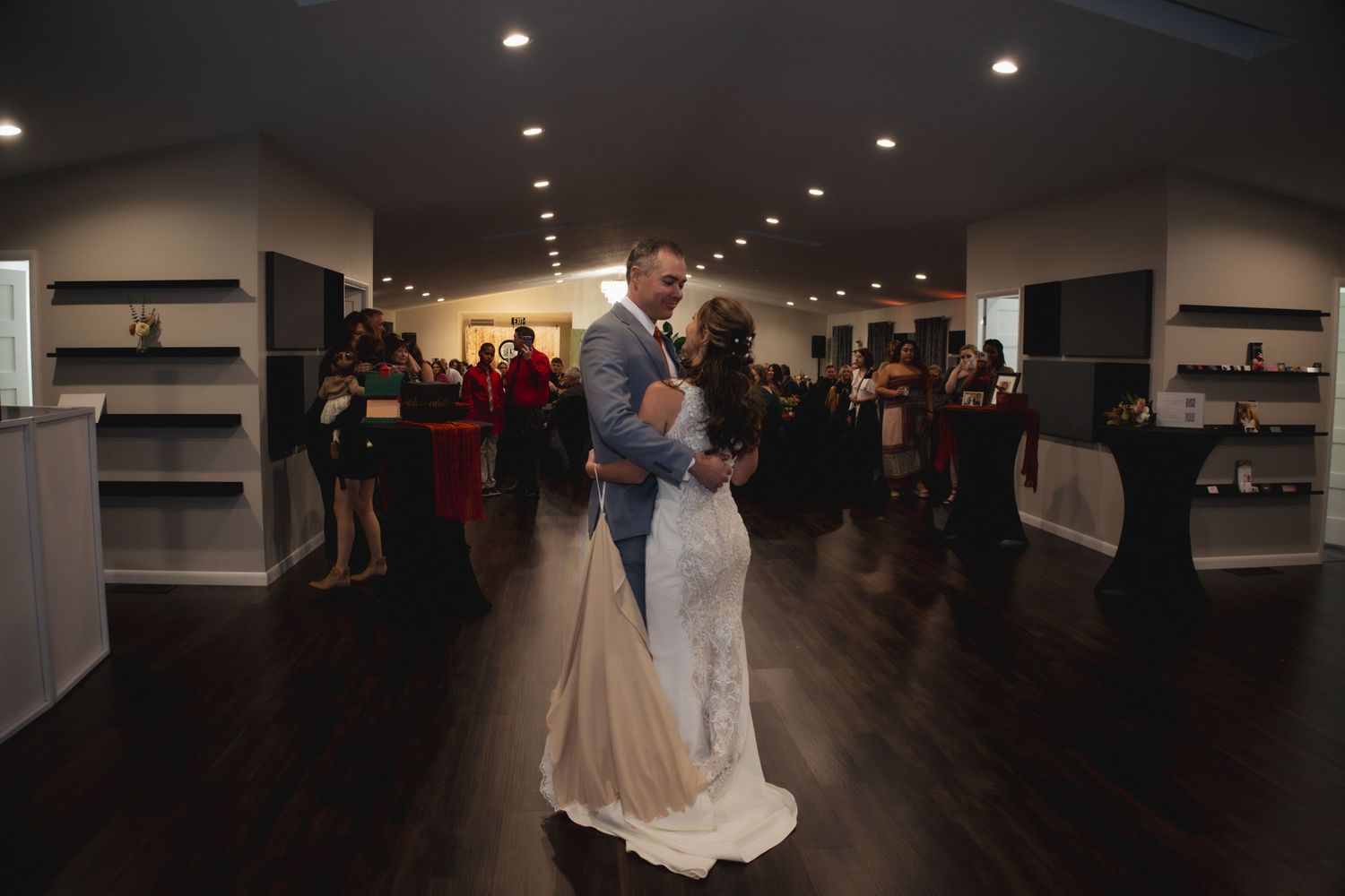 Couple dancing in elegant reception venue with dark hardwood floors.