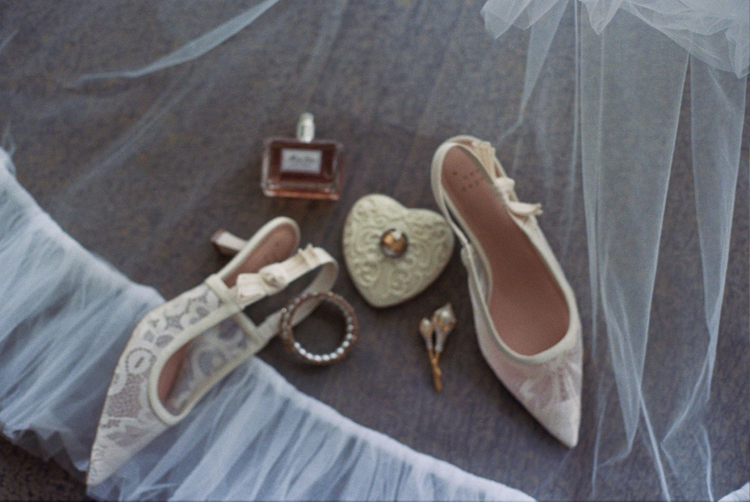 A collection of vintage white baby shoes and booties arranged on a gray fabric background.
