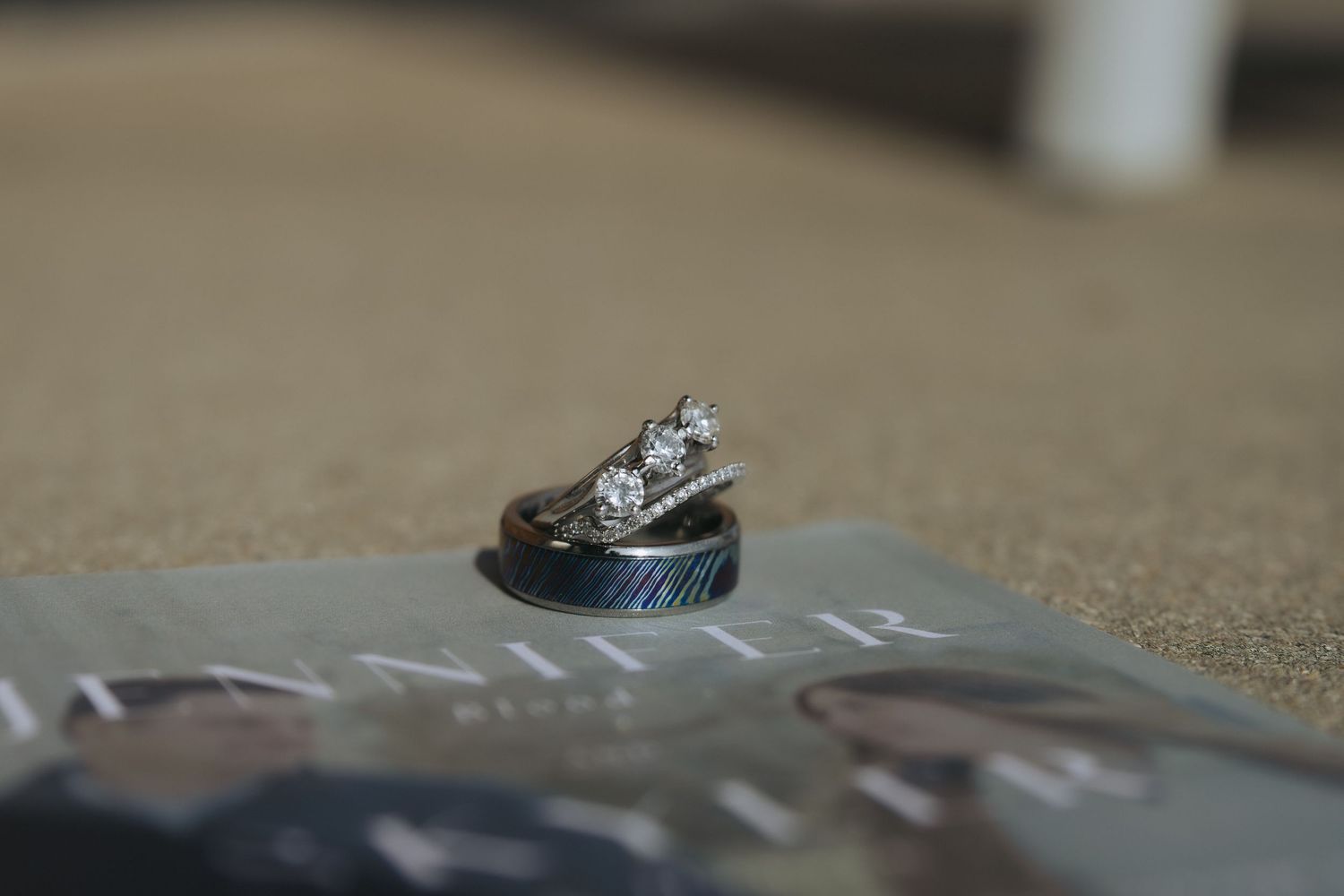 Two wedding rings sit on a textured gray surface in an artistic macro photograph.