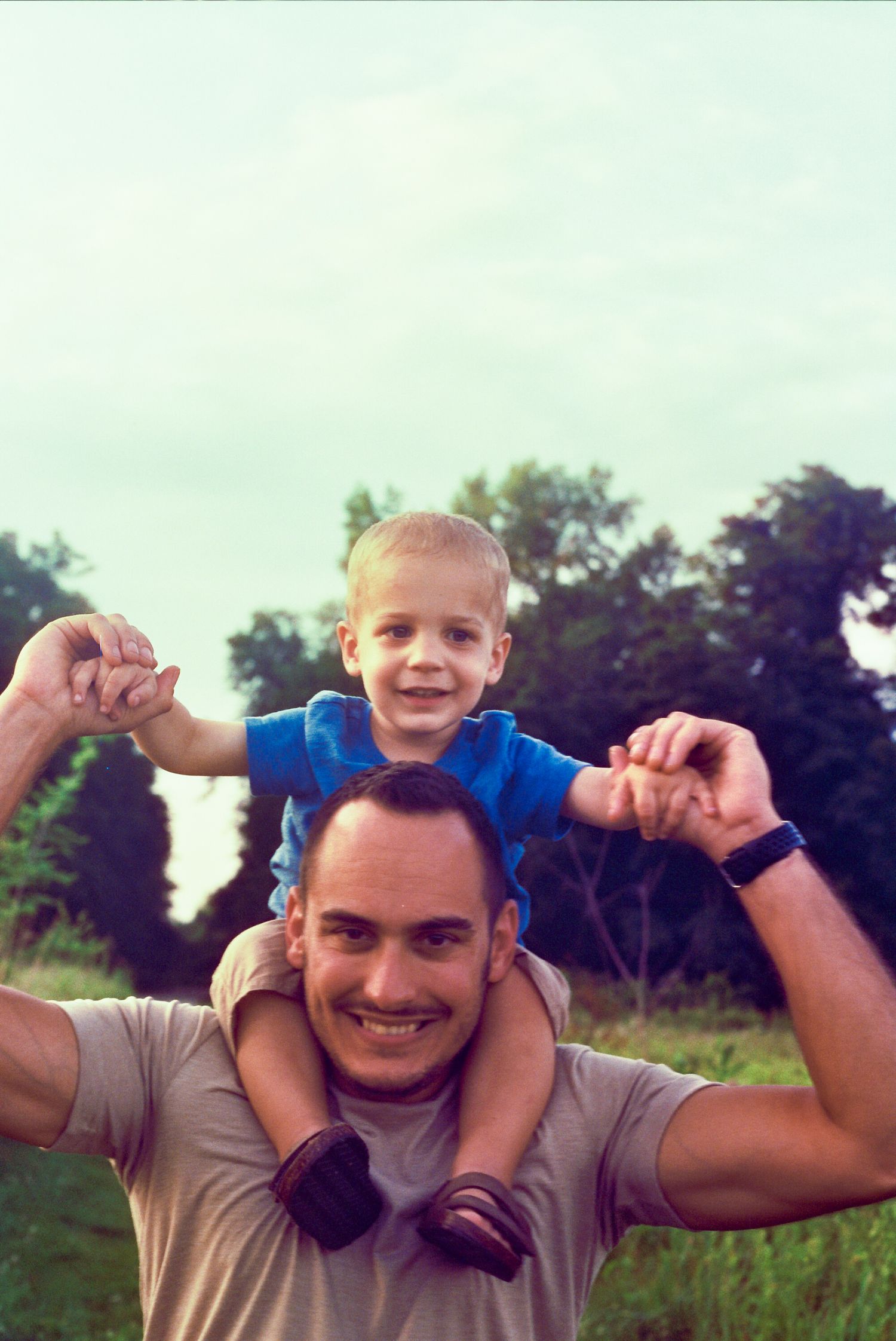 A heartwarming sequence shows someone giving a joyful child a shoulder ride in a grassy outdoor setting during daytime.