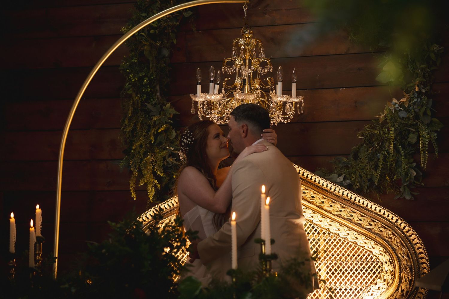 A romantic wedding moment captured in warm lighting with a chandelier and candlelight creating an intimate atmosphere.