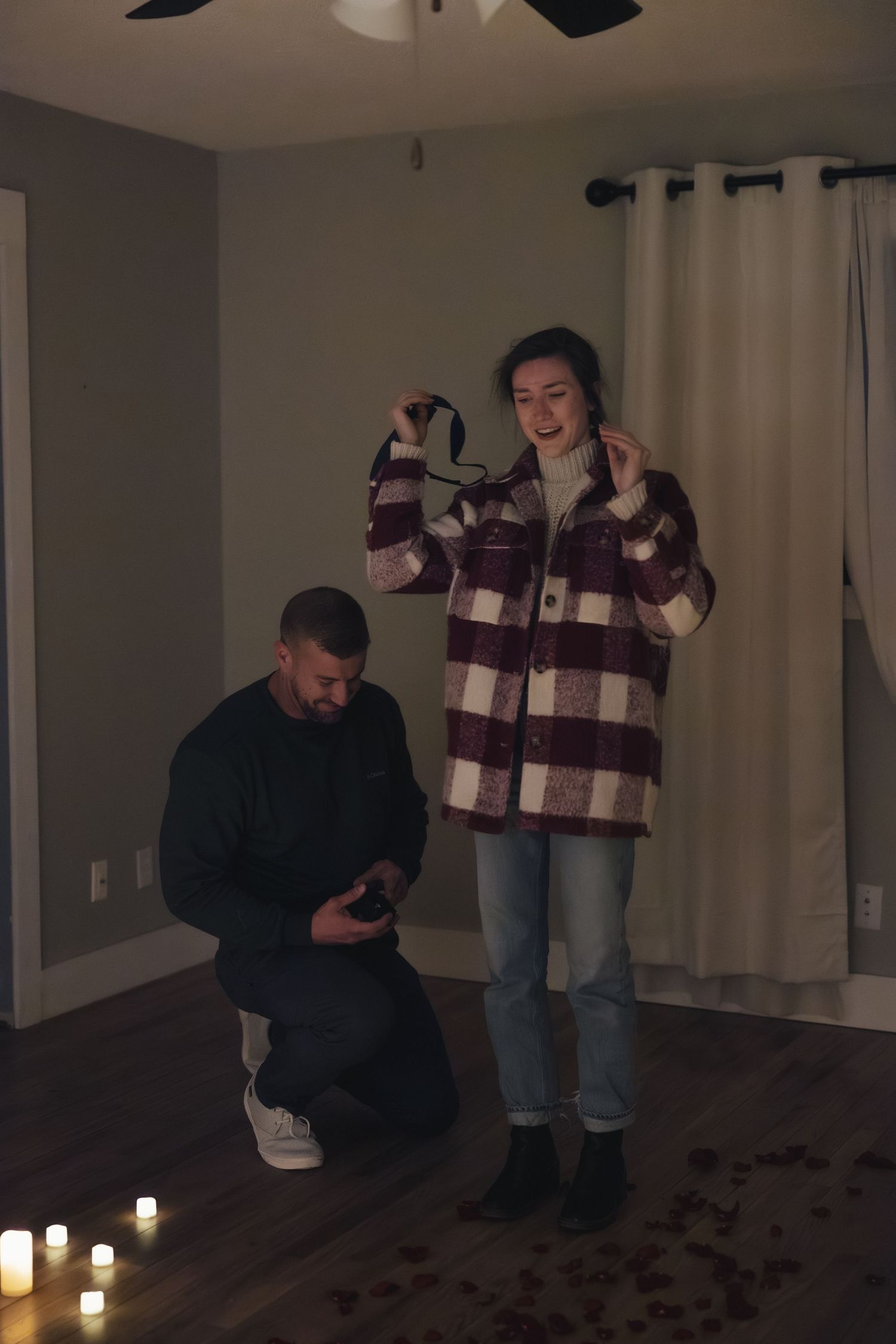 A candlelit proposal scene shows a person kneeling in front of another in a dimly lit room.